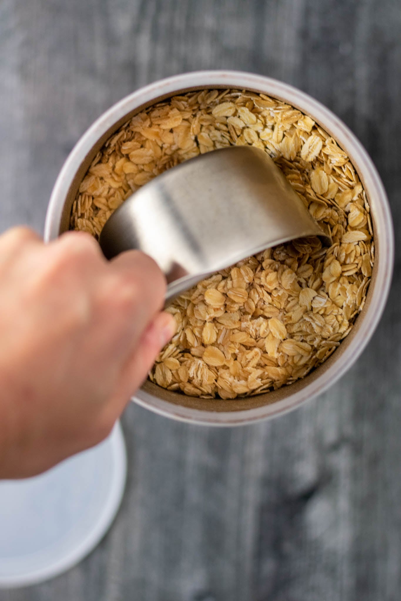 Overhead of scooping a cup of oats from oat container