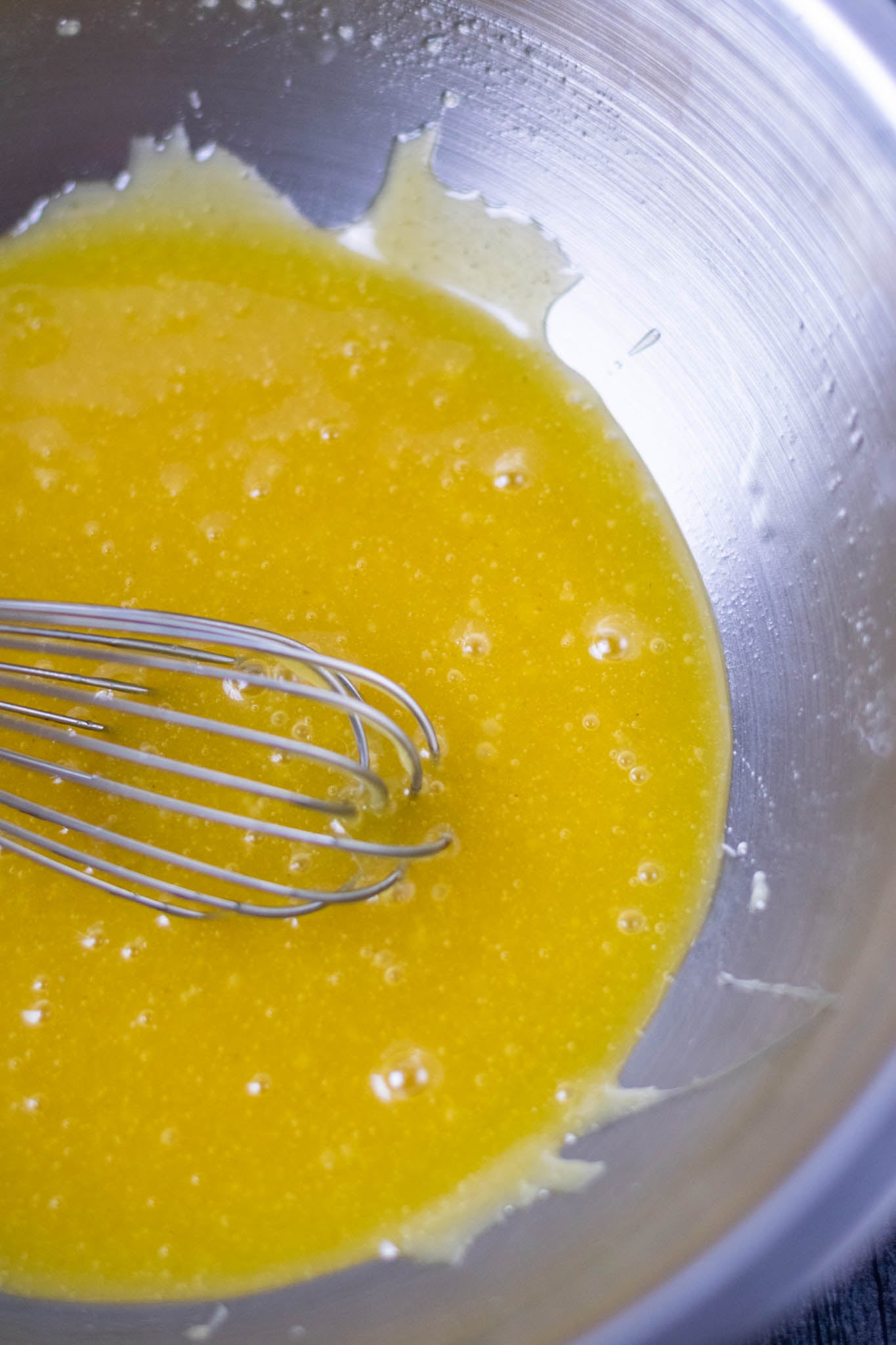Whisked liquid ingredients in mixing bowl with whisk