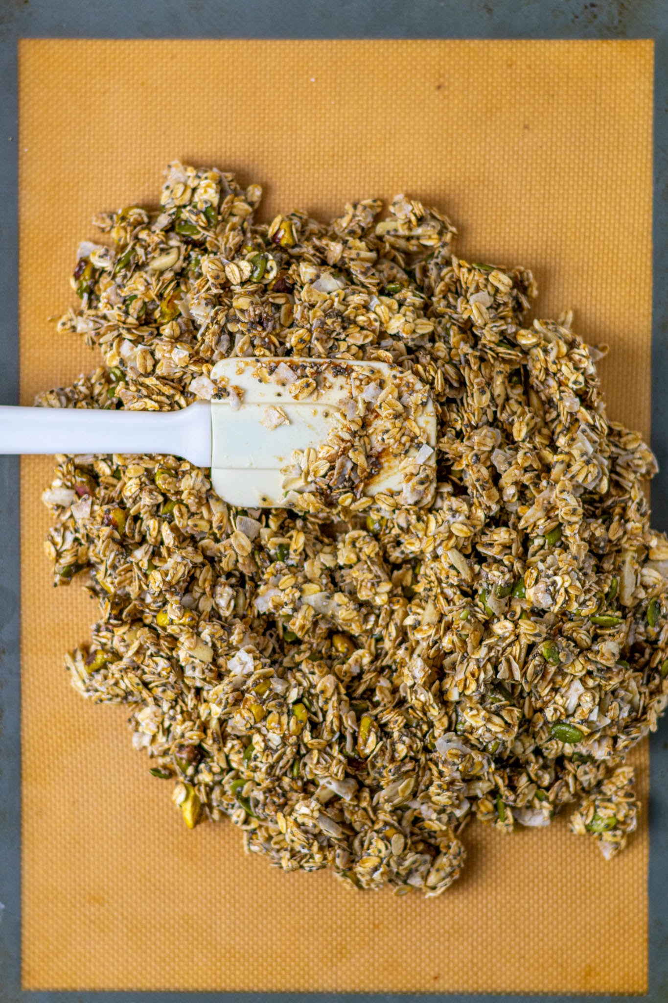 Spatula spreading sourdouogh discard granola on silicone baking mat