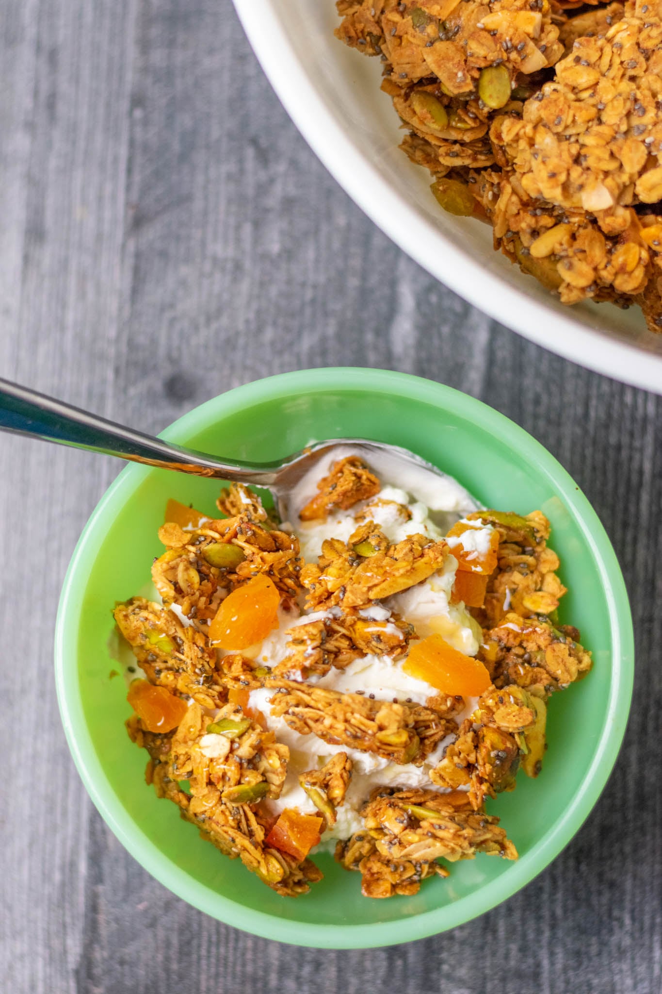 Overhead of Easy Sourdough Discard Granola recipe in small green bowl with yogurt