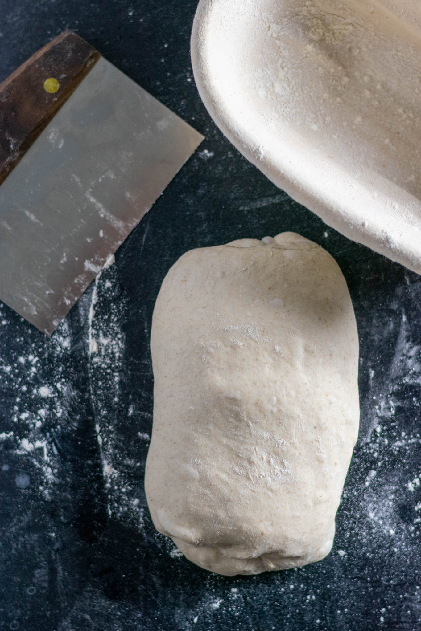 Shaped dough in batard, oval shape on counter with dusted flour