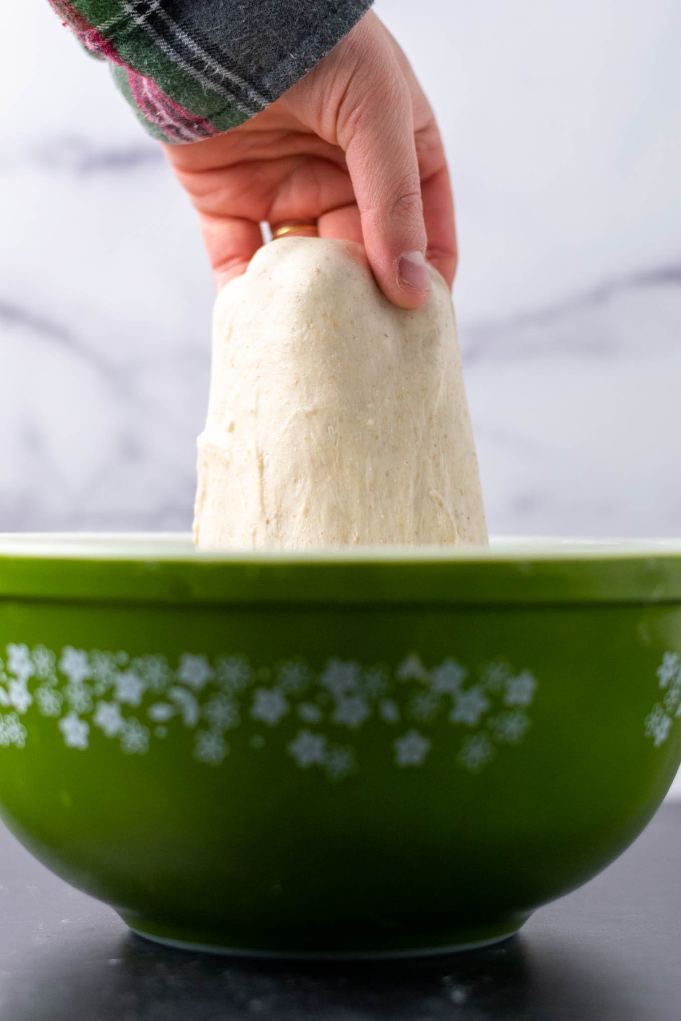 Hand stretching dough in mixing bowl during mixing