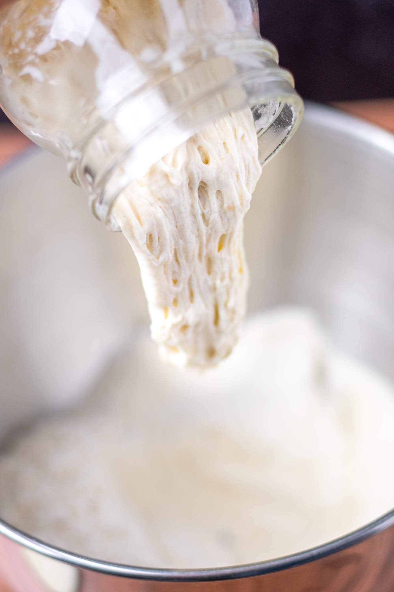 Pouring bubbly levain into bowl of dry ingredients