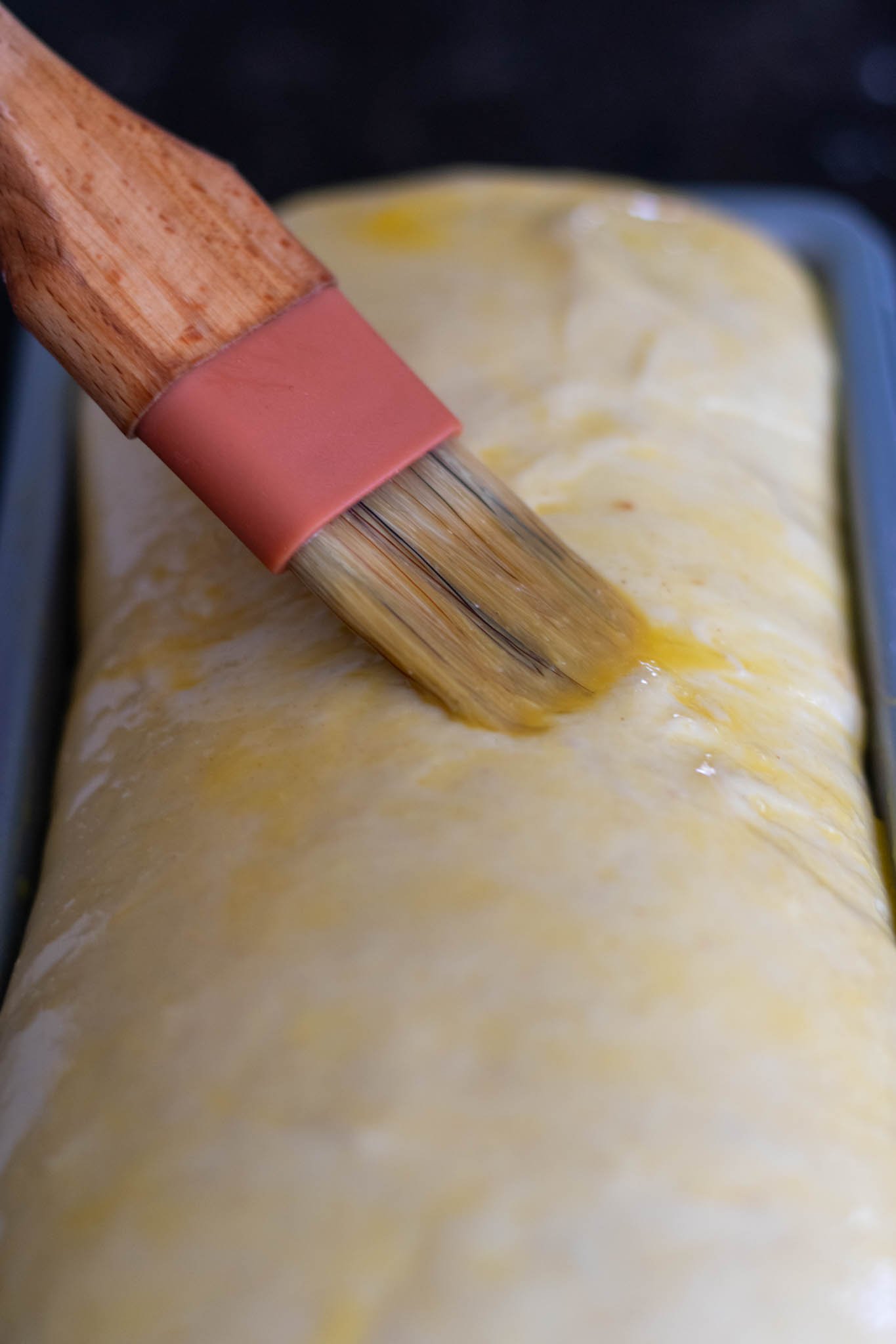 Brushing on egg wash to dough in bread pan before baking
