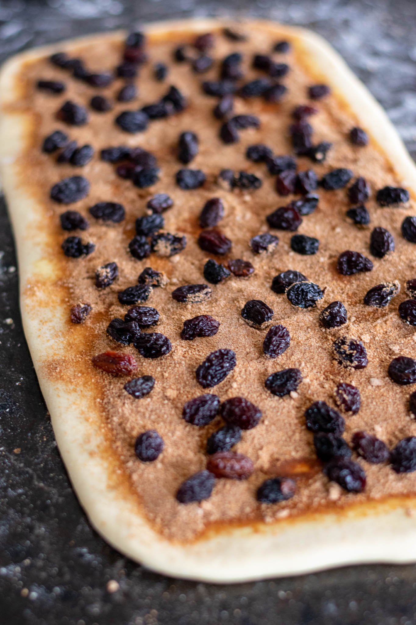 Closeup of raisins added to rolled out dough with filling added
