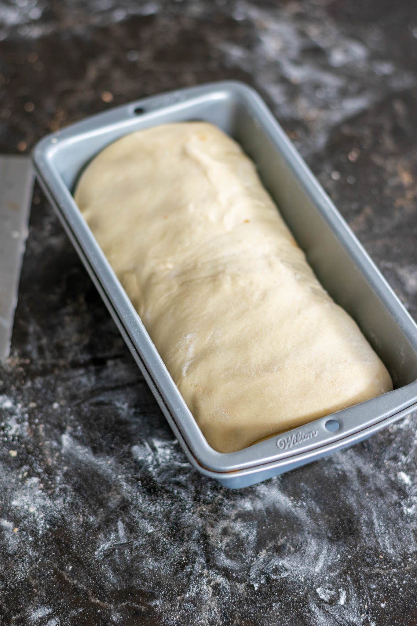 Dough shaped and placed in bread pan on floured counter