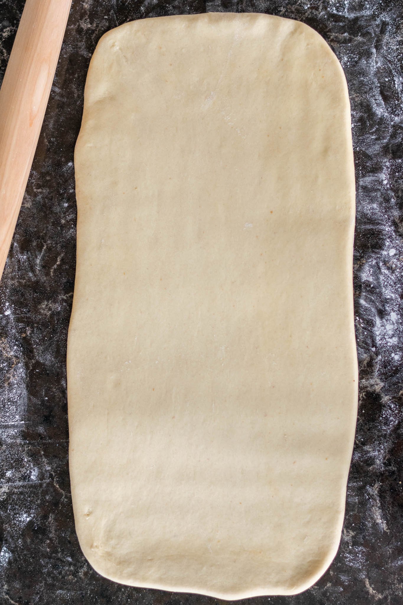 Dough rolled out on floured counter into large rectangle with rolling pin