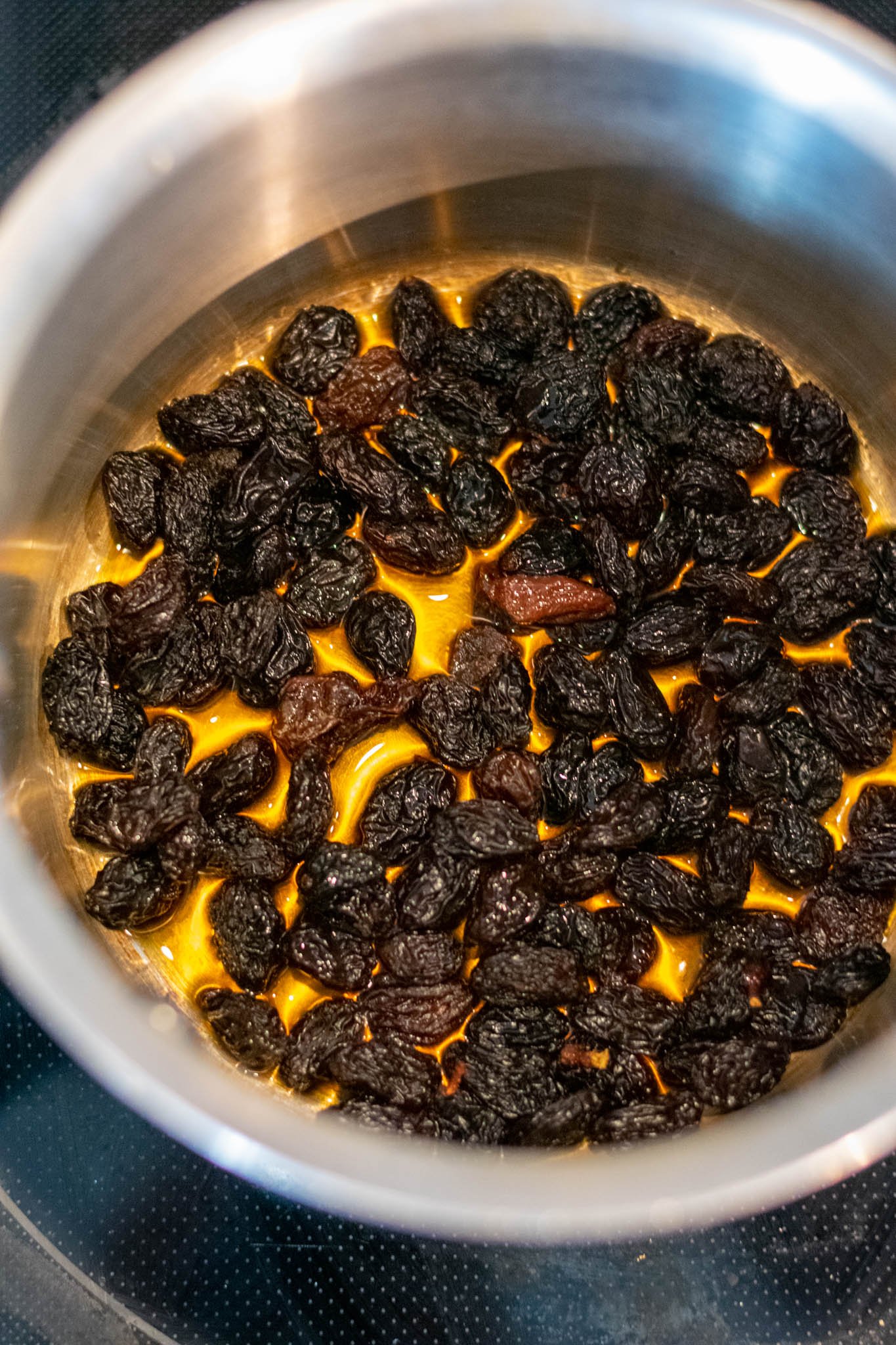 Stainless steel pot on stove with raisins and rum