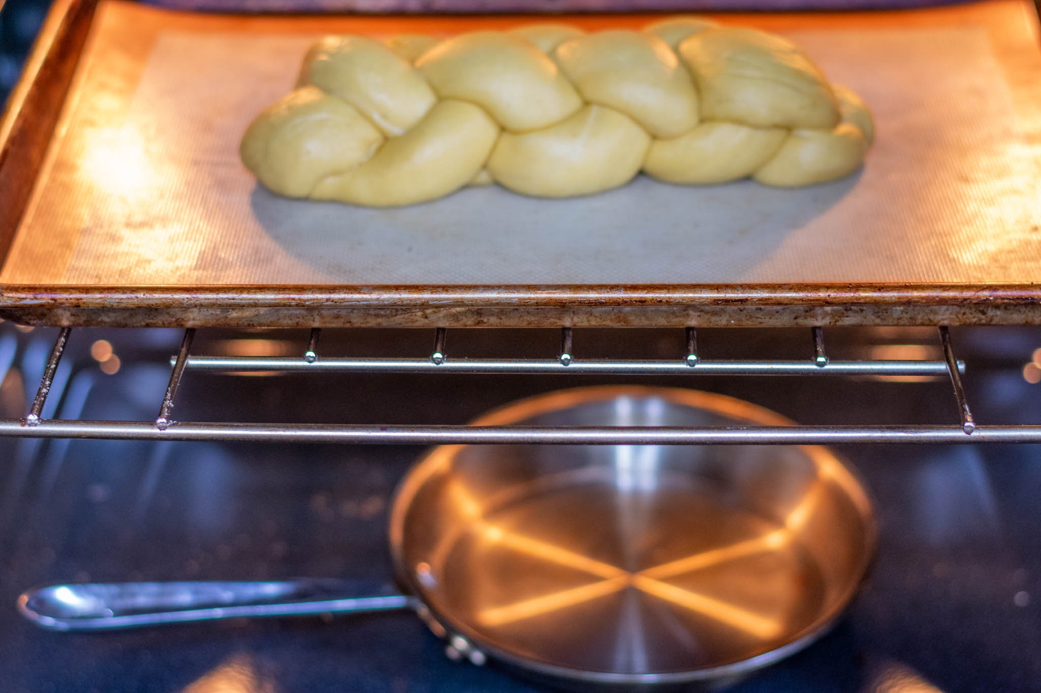 Sourdough challah proofing in oven with pan for humidity