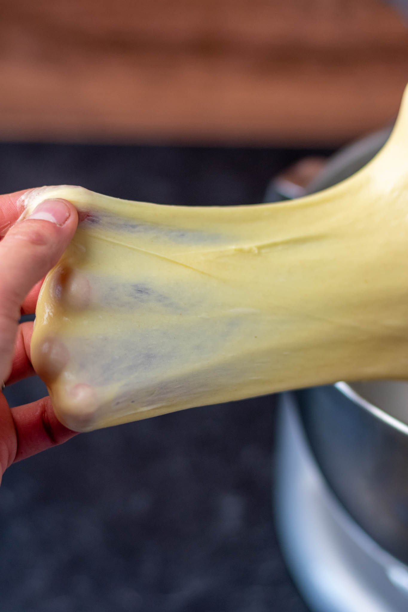 Hand pulling sourdough brioche dough for windowpane test