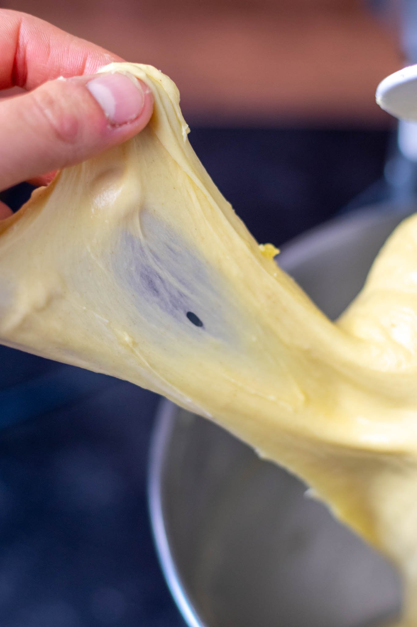 Hand pulling brioche dough and starting to tear- does not pass windowpane test