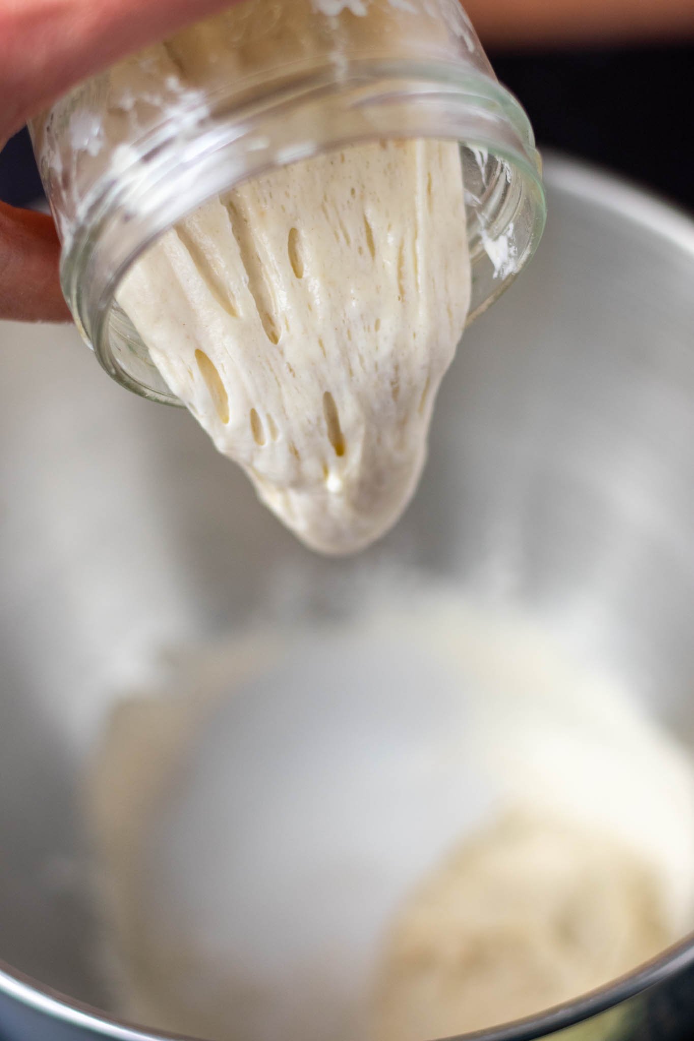 Pouring levain or sourdough starter from jar into stand mixer bowl
