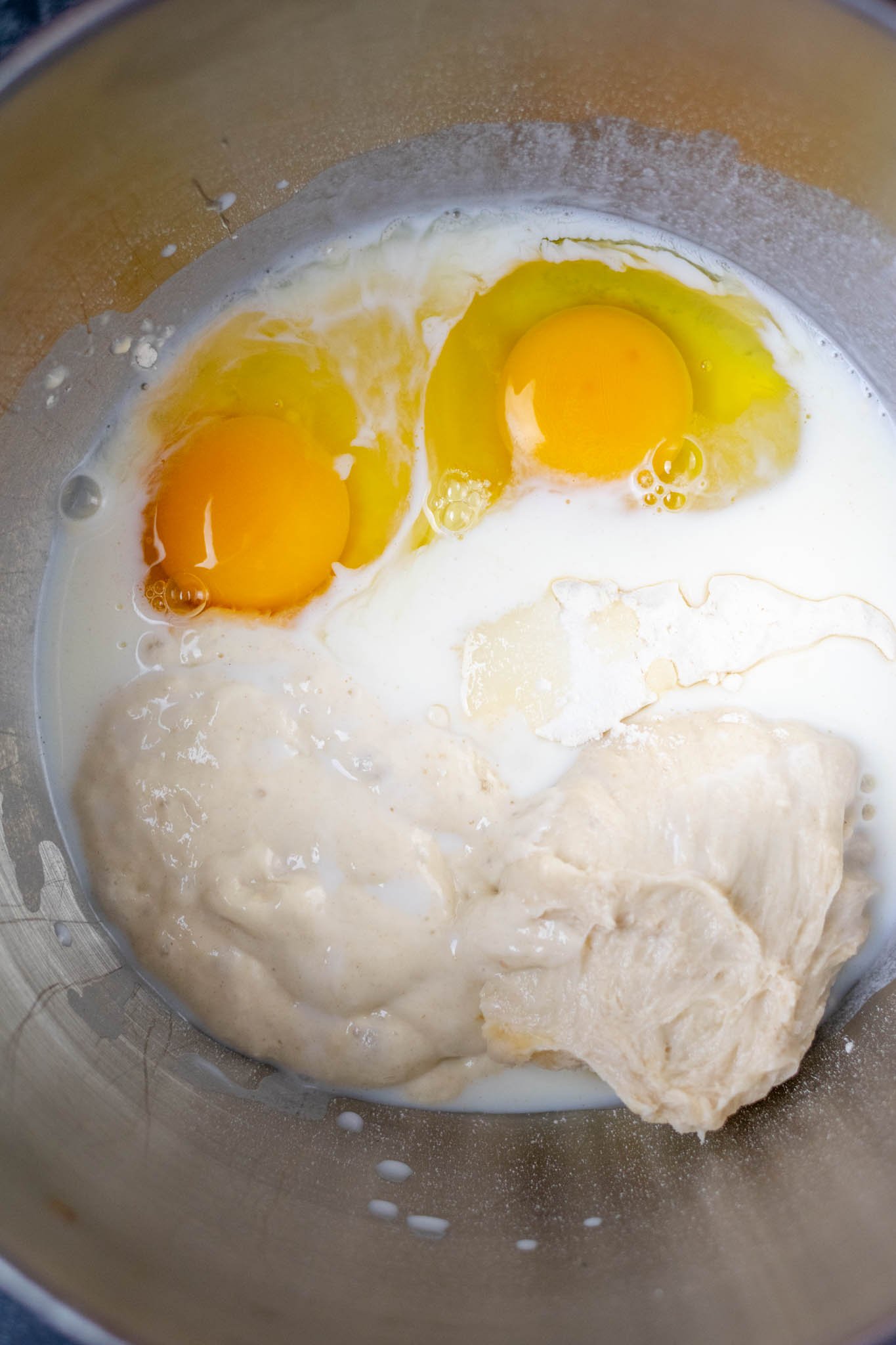 Brioche ingredients in stand mixer bowl before mixing including eggs