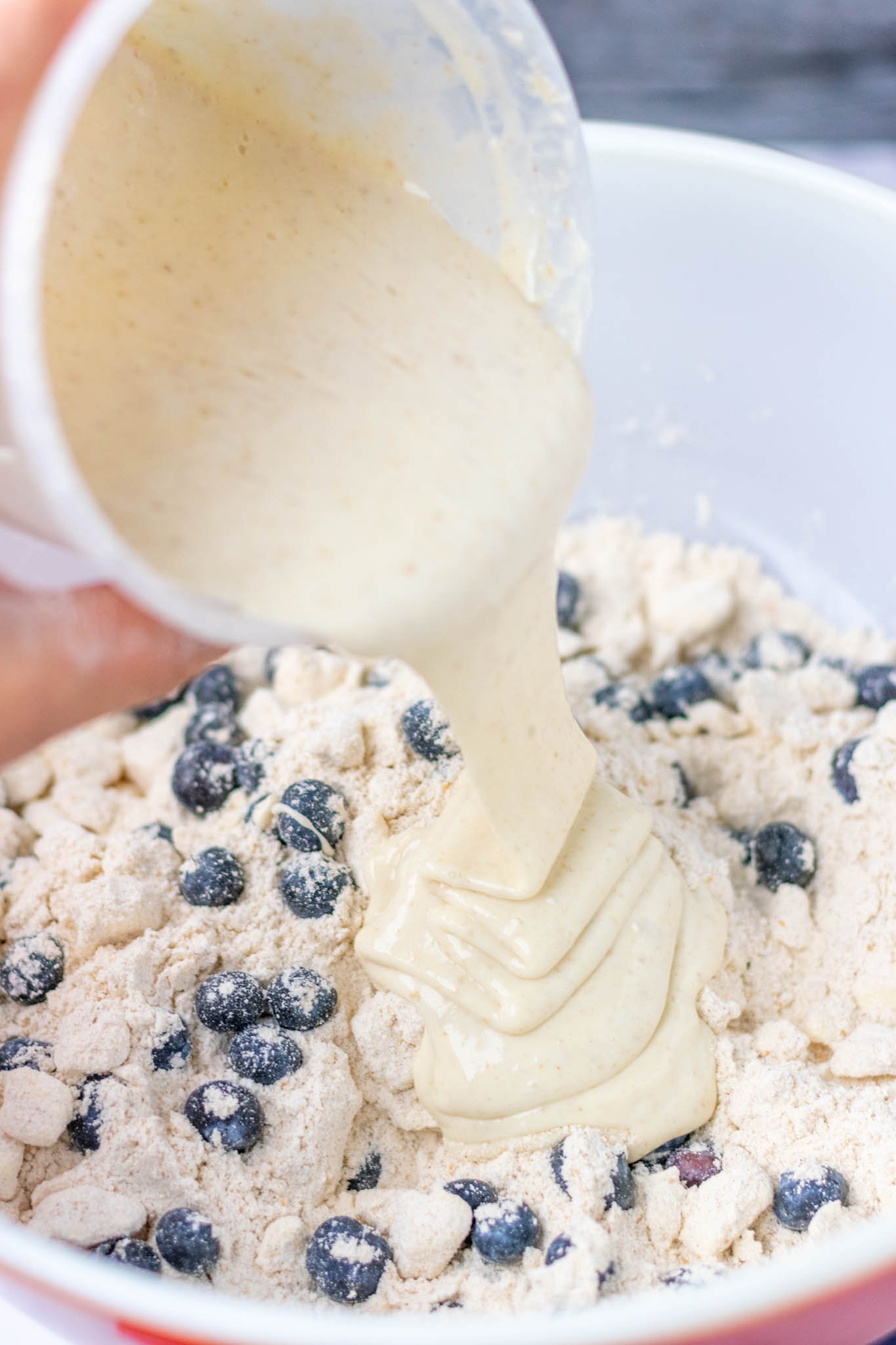 Pouring sourdough discard into bowl with blueberries and ingredients