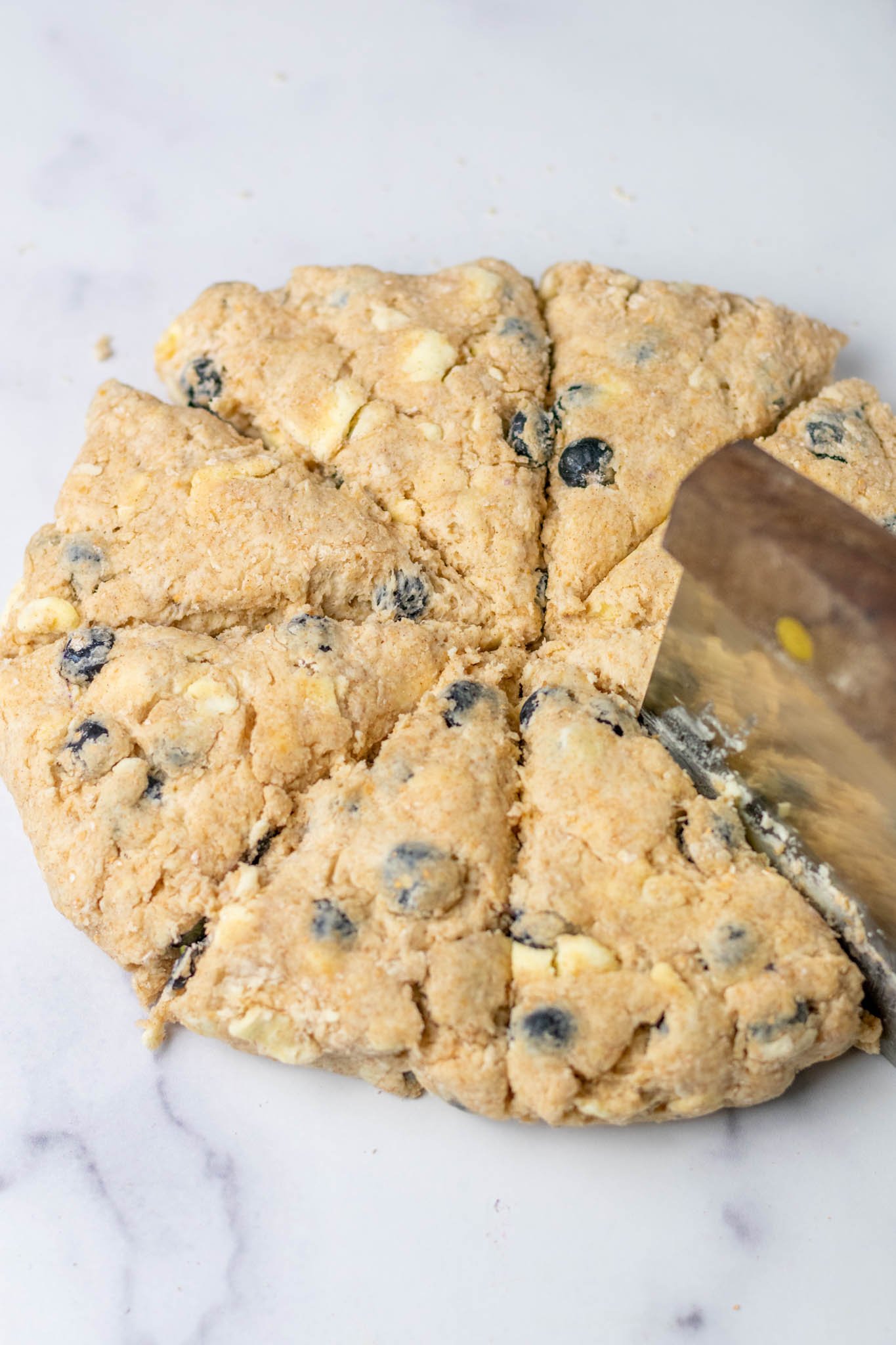 Bench scraper dividing Sourdough discard blueberry scones into eight pieces