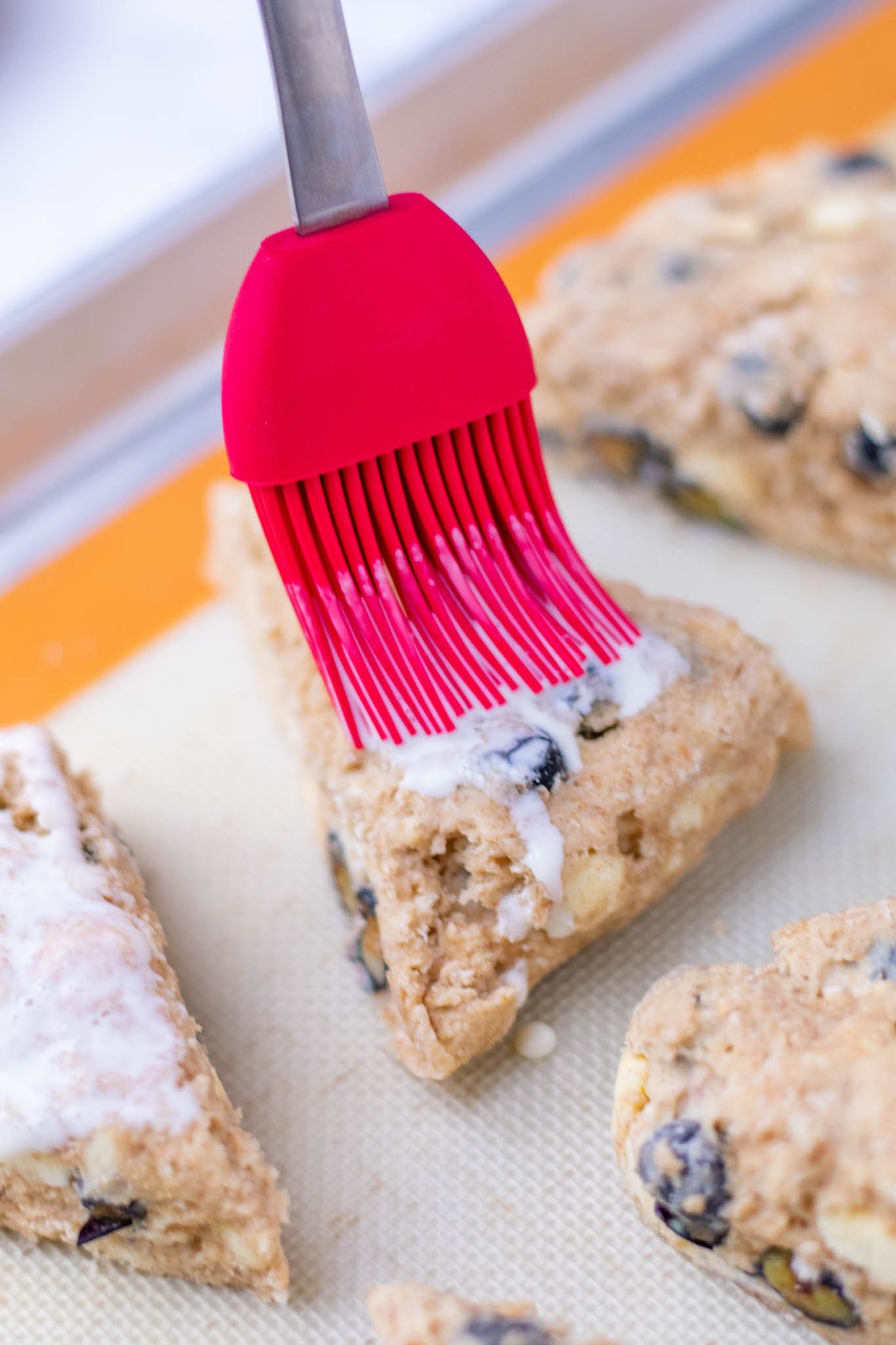 Pastry brush brushing heavy cream onto sourdough discard blueberry scones