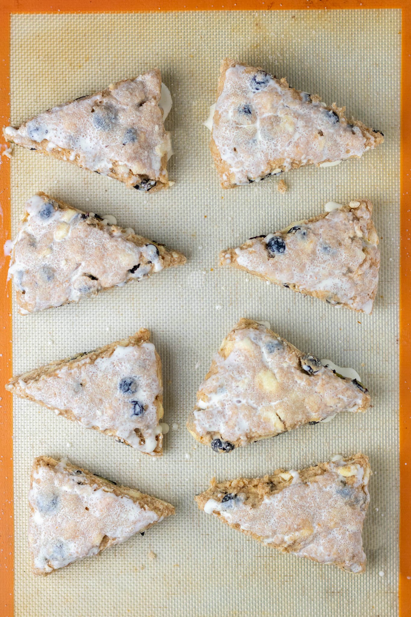 Cream and sugar brushed on Sourdough discard blueberry scones on half sheet pan