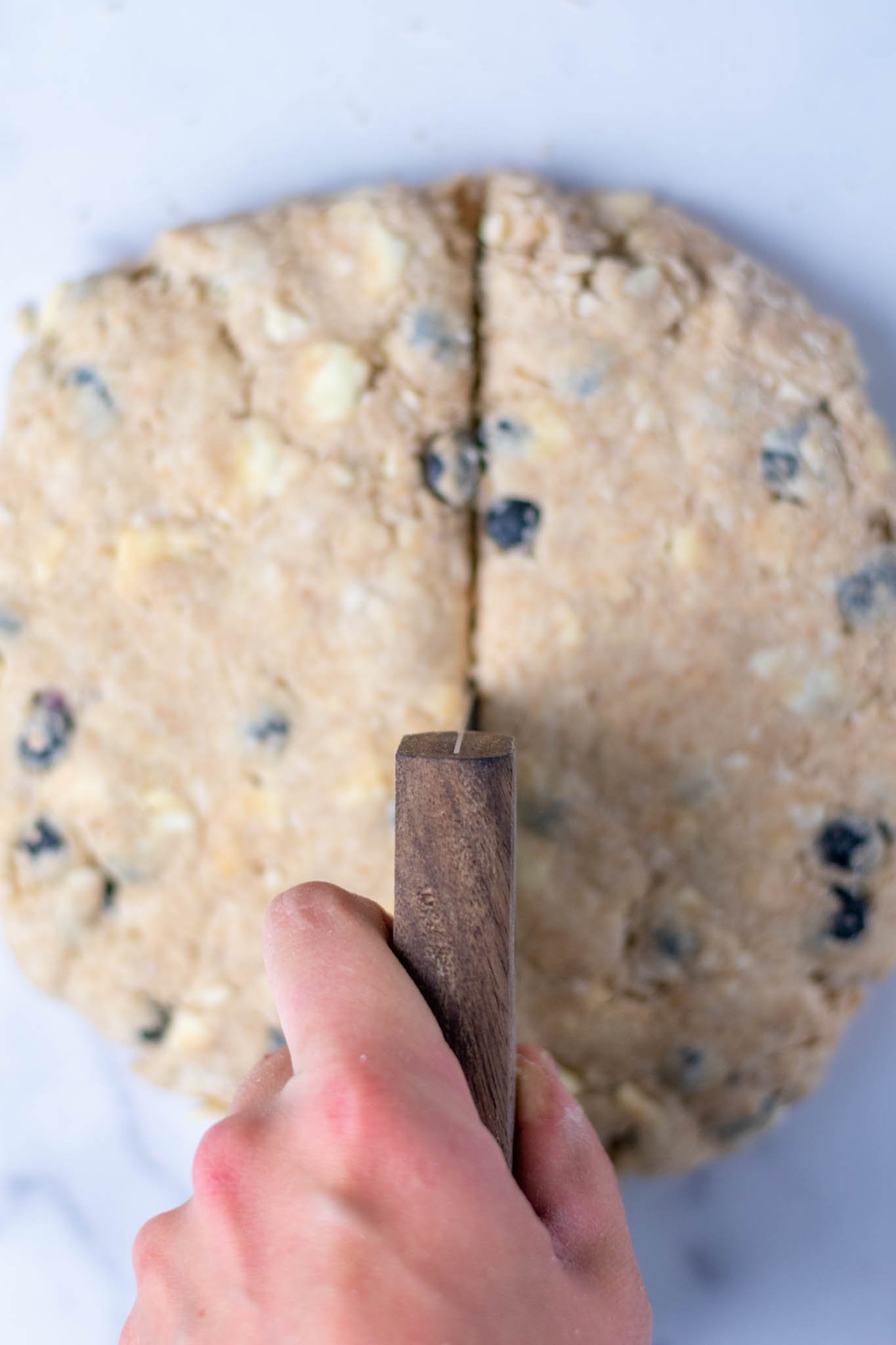Dividing Sourdough discard blueberry scones in half with bench scraper