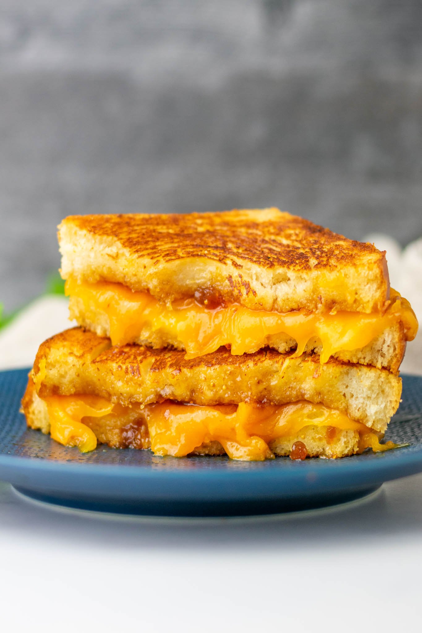Cut, gooey grilled cheese sandwich on plate using sourdough sandwich bread