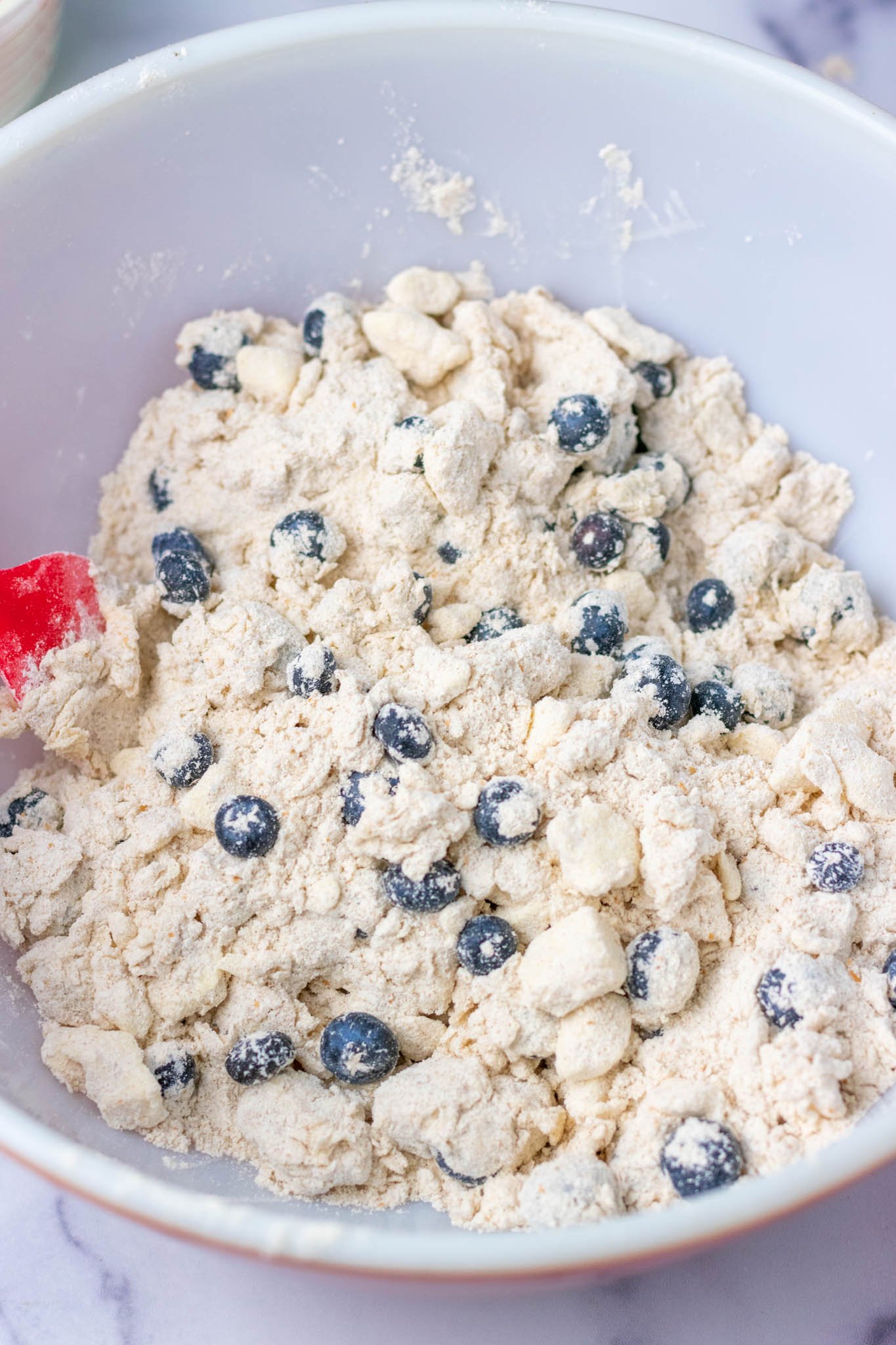 Sourdough discard mixed in bowl with blueberries and spatula