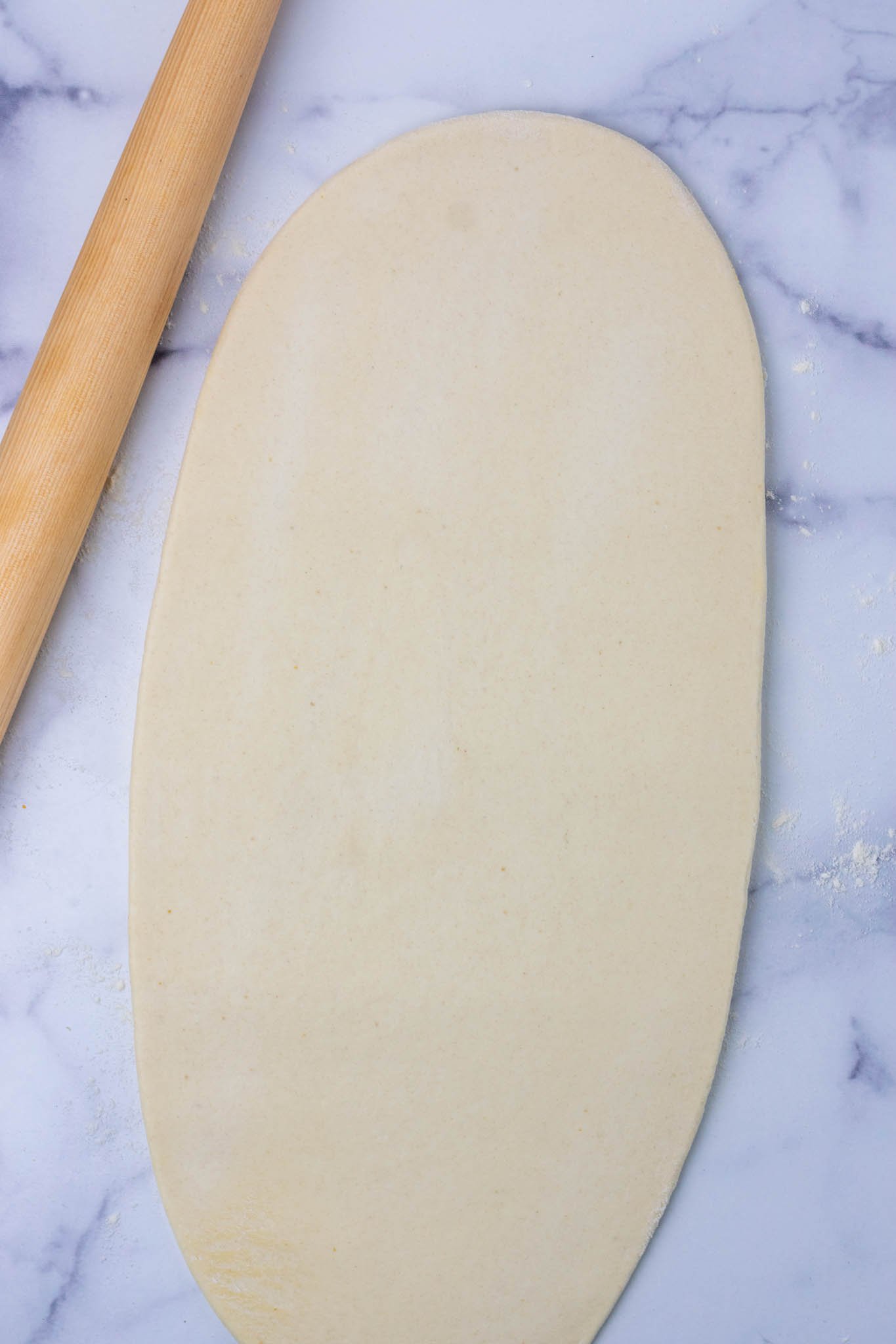 Rolled out sourdough sandwich bread into long oval with rolling pin