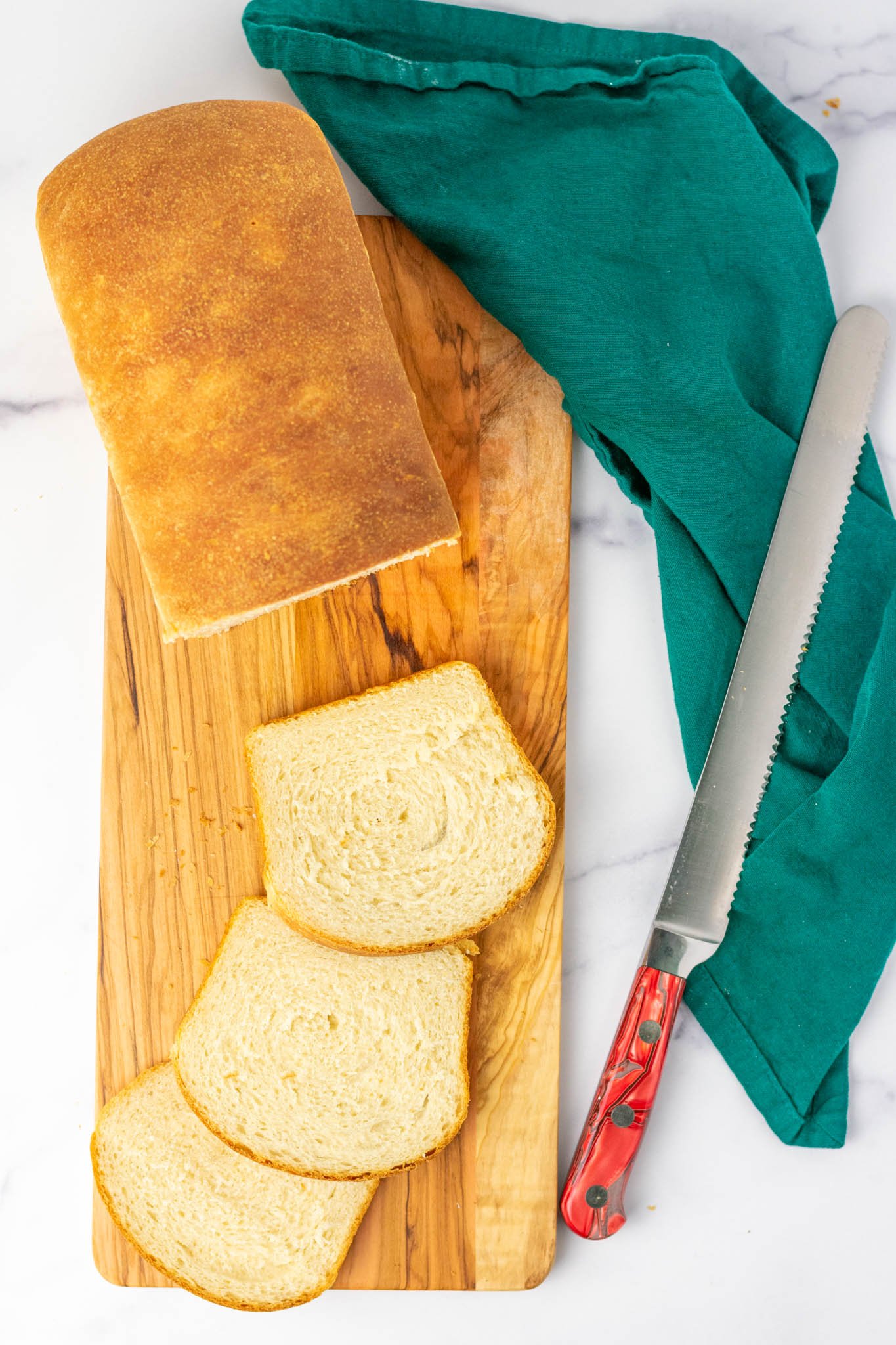 Slices of sourdough sandwich bread on platter with bread knife and towel