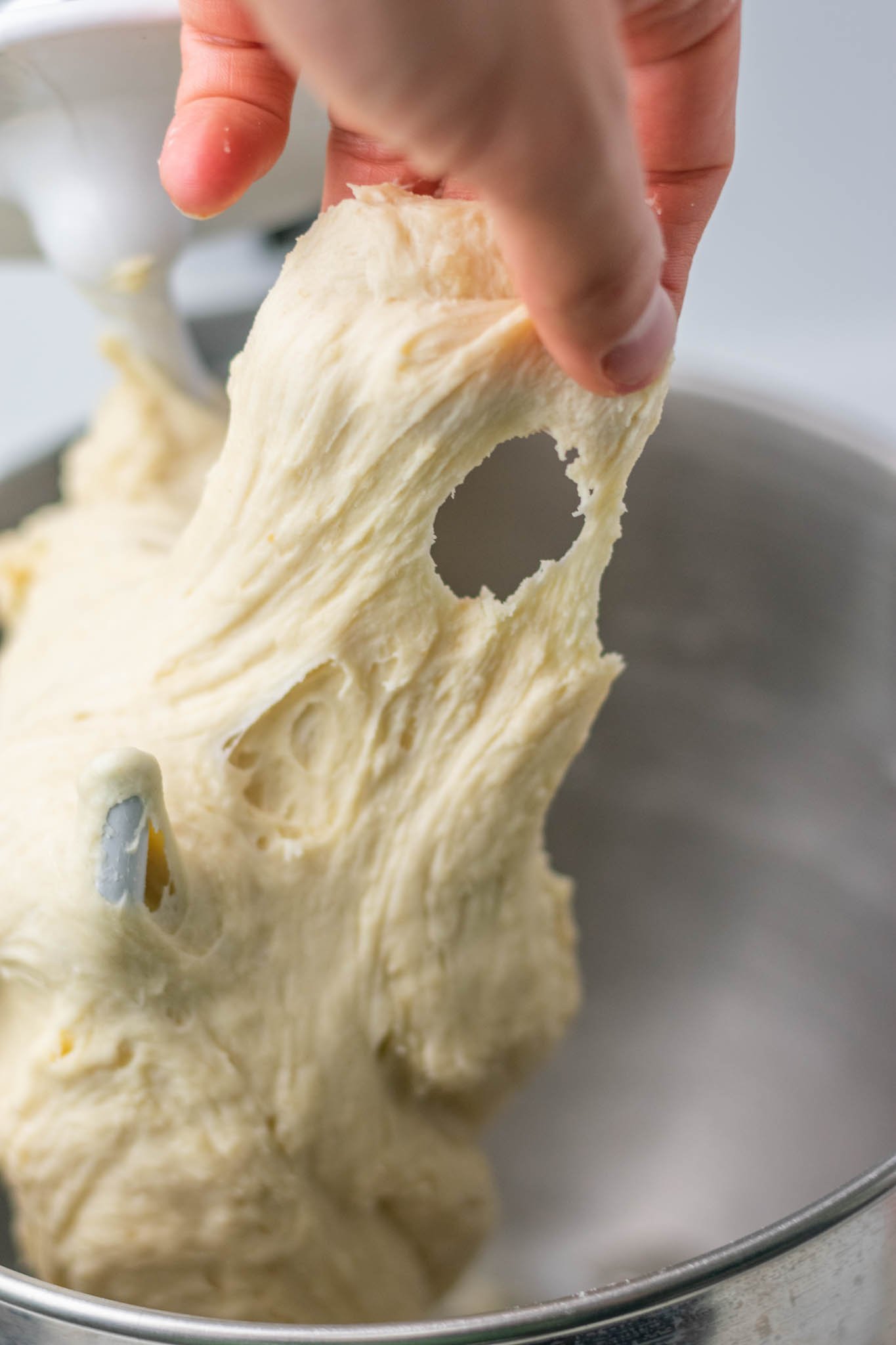 Hand pulling sticky sourdough sandwich bread dough in stand mixer bowl