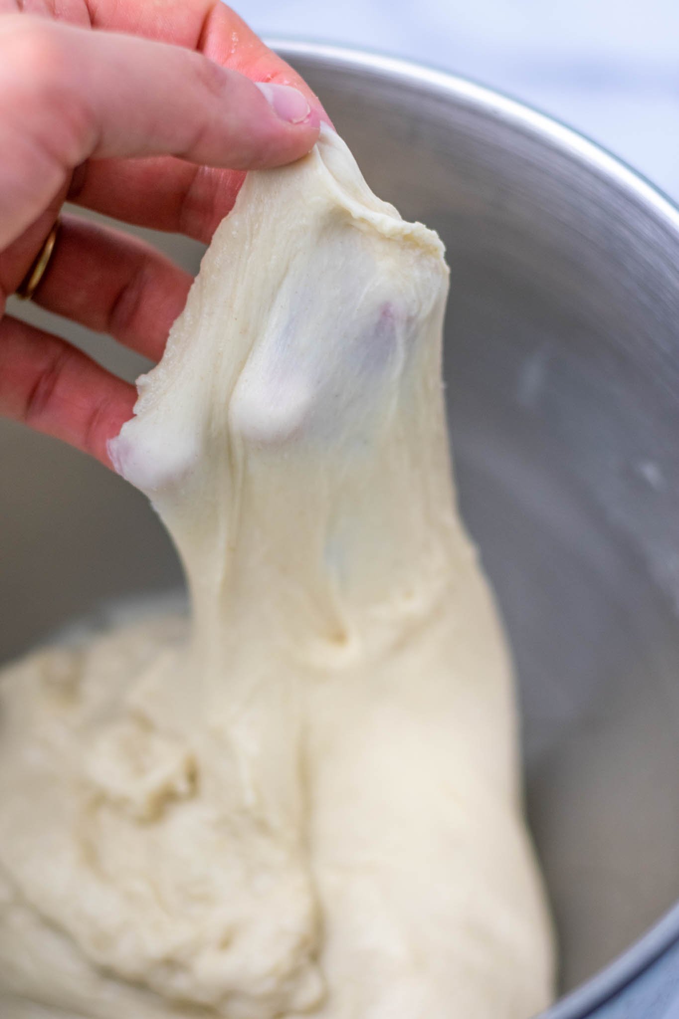 Hand pulling up dough for windowpane test