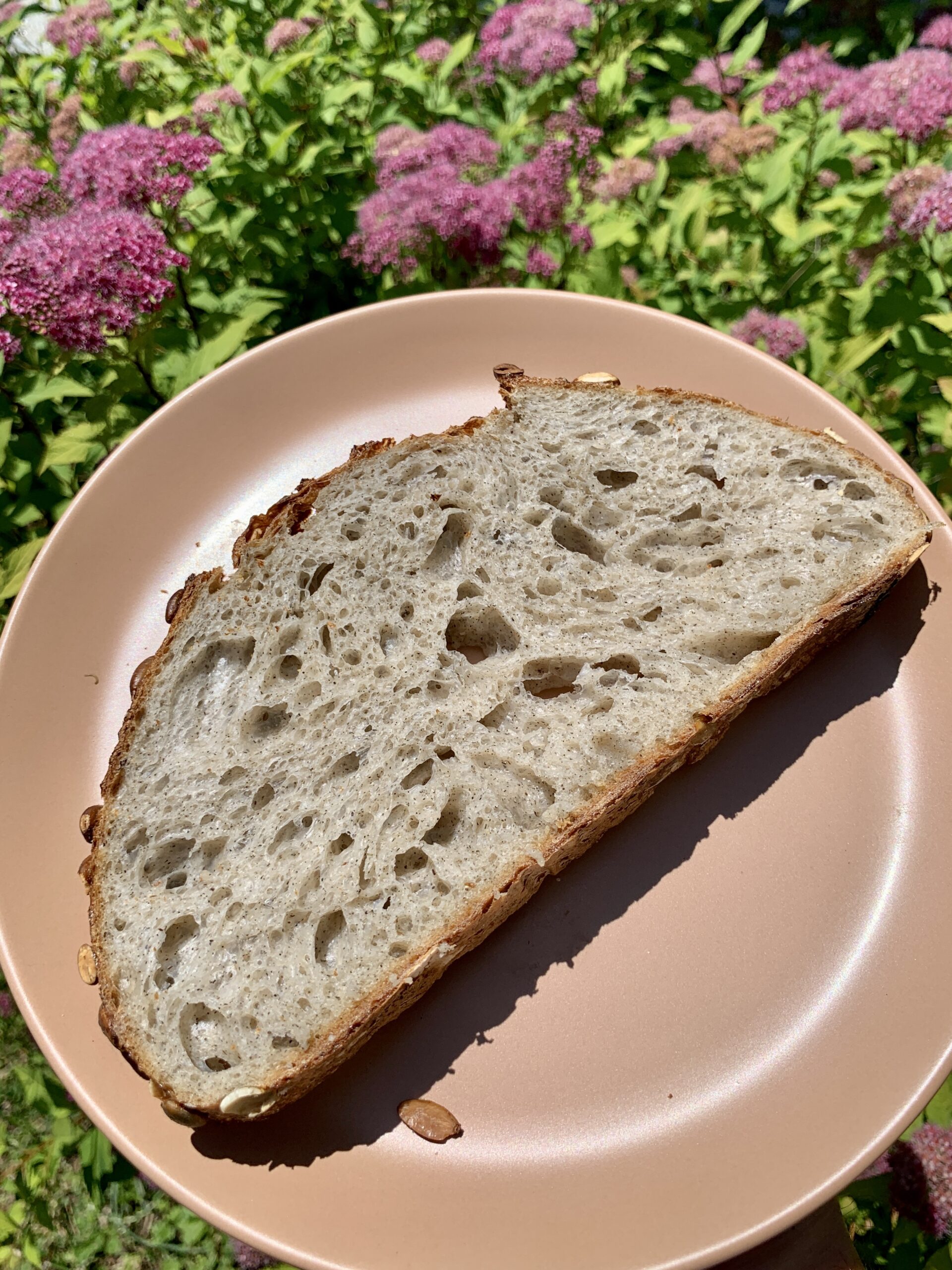 Slice of buckwheat sourdough on plate with flowers in background
