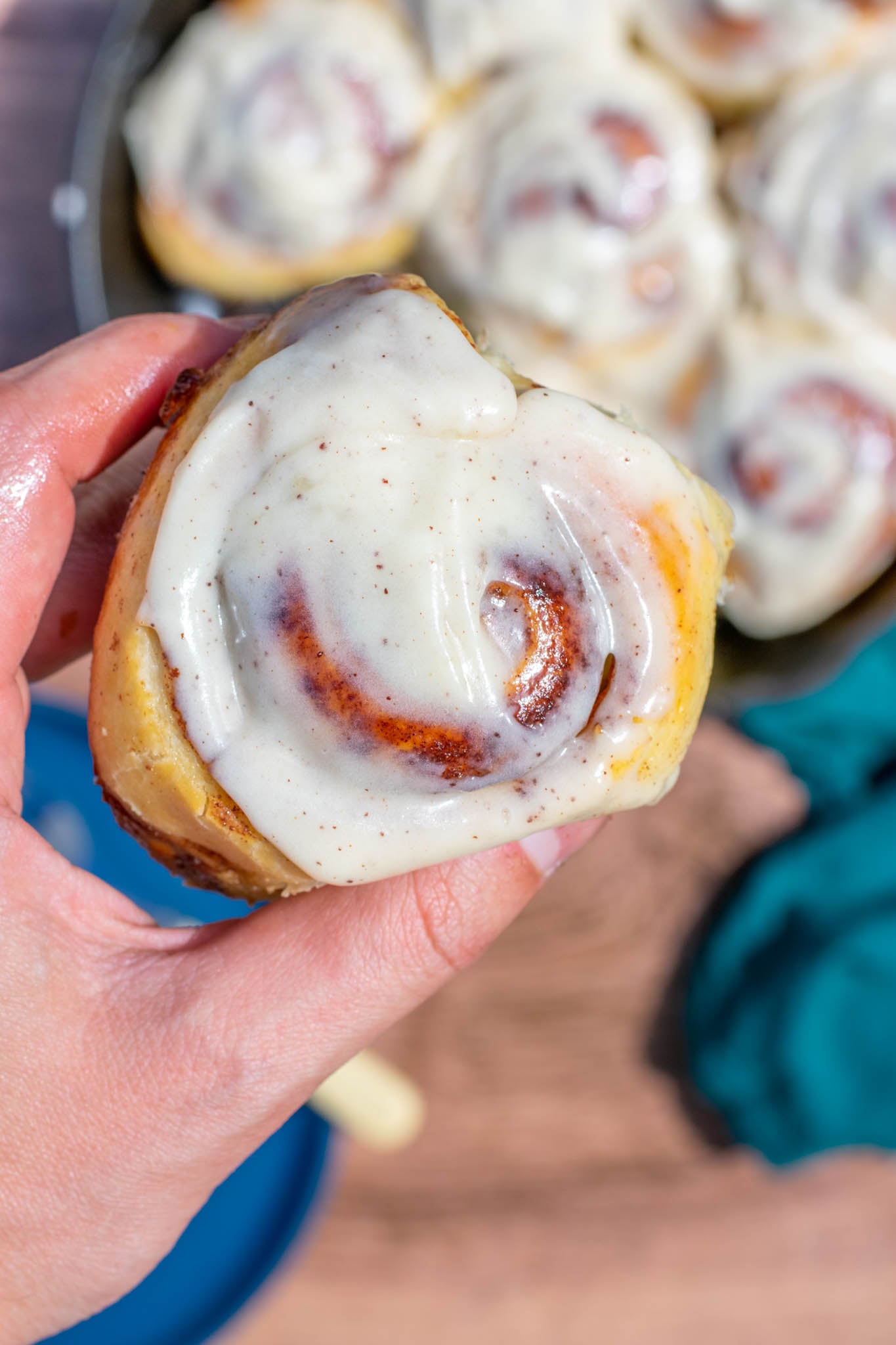 Hand holding up a sourdough cinnamon roll