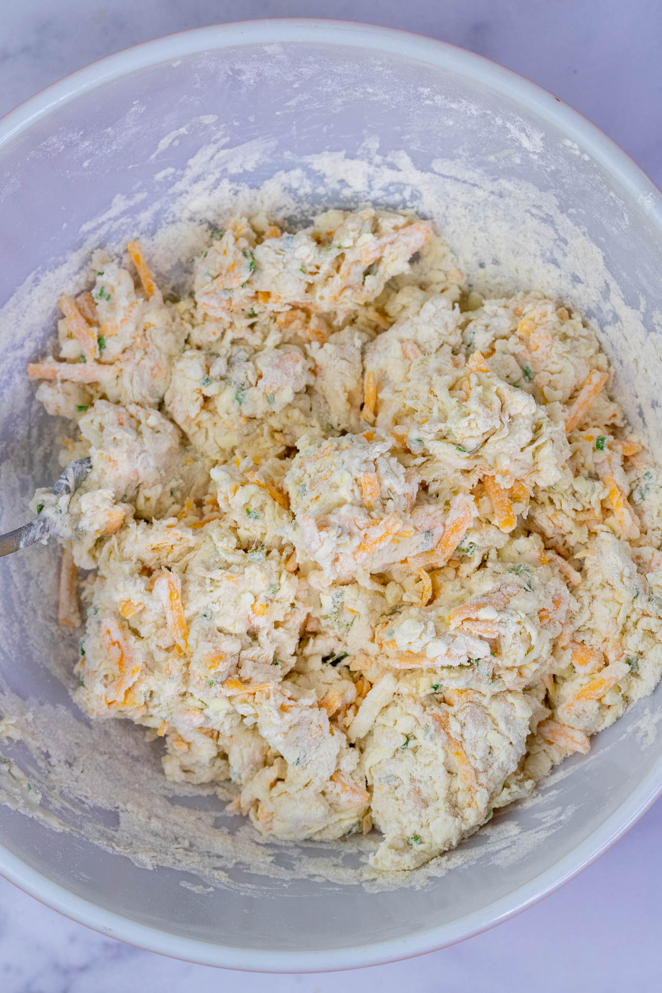 Mixed sourdough biscuit dough in mixing bowl before kneading. The dough is shaggy and barely together.