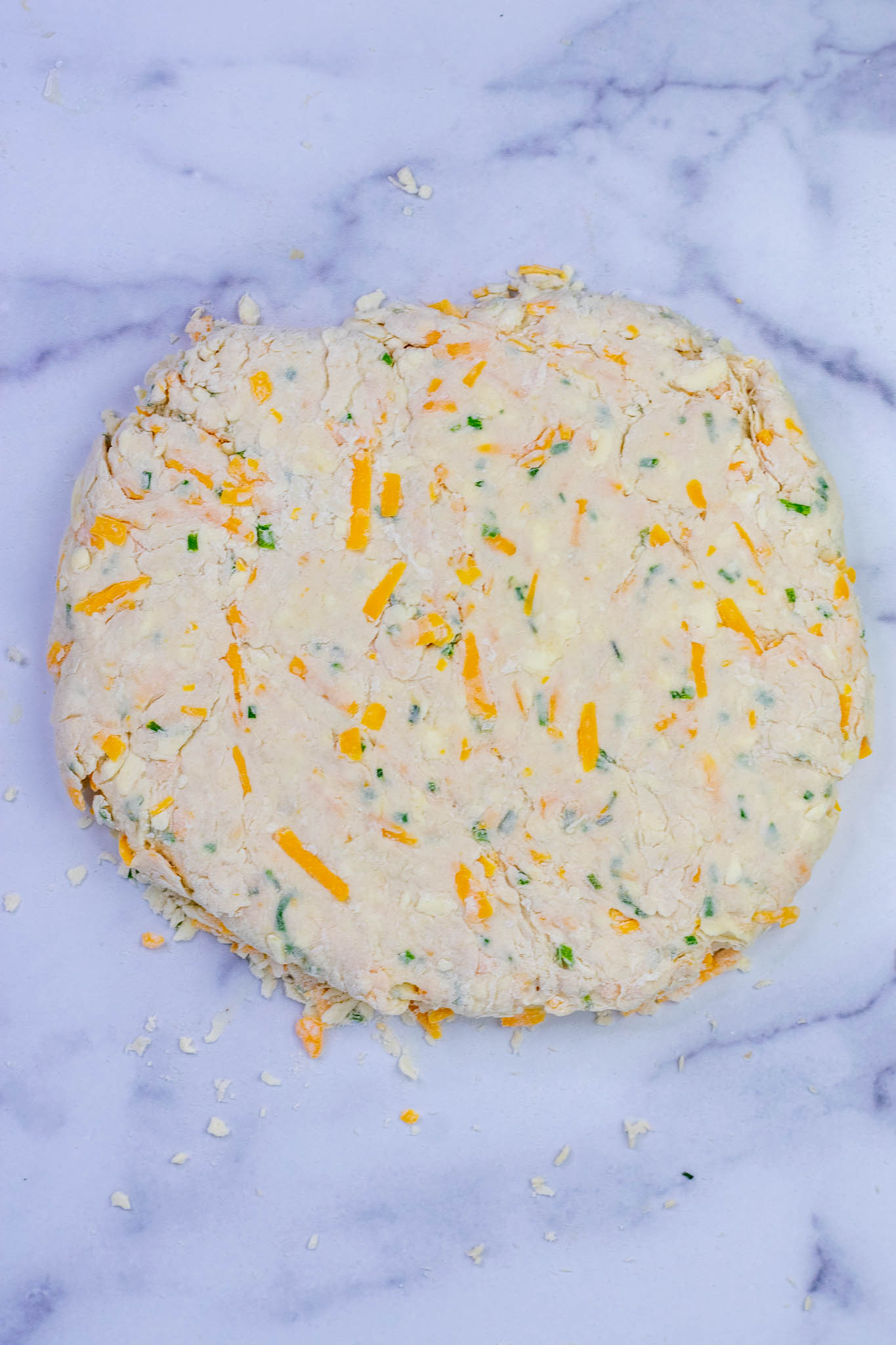 Patted down sourdough biscuit dough into a circle on countertop