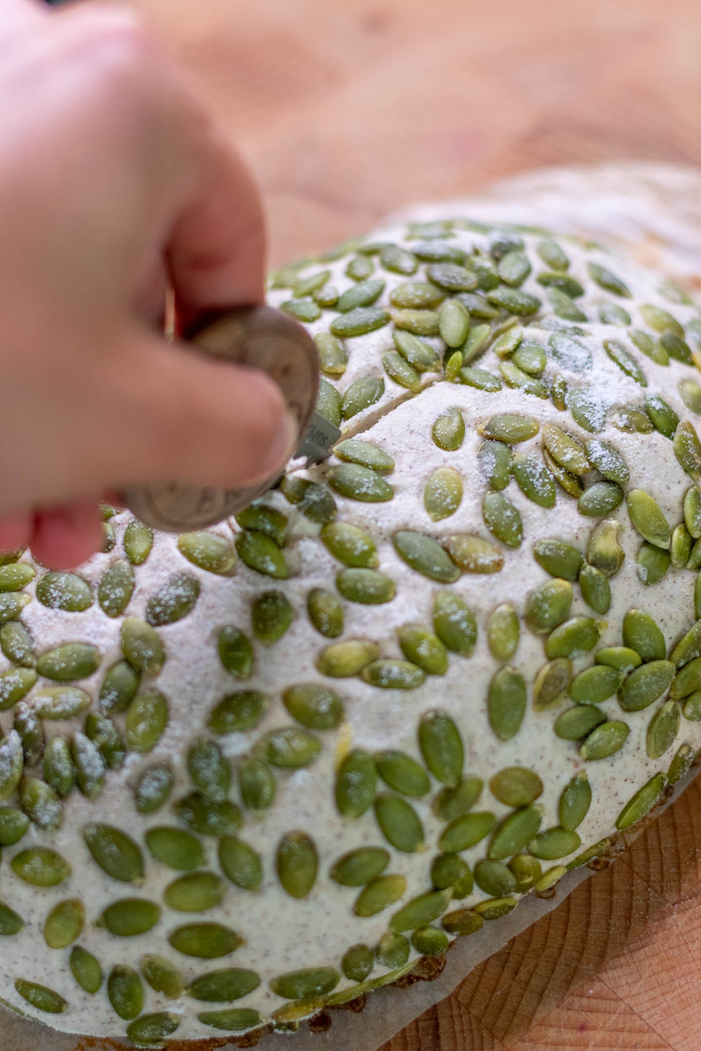 Hand using bread lame to score buckwheat sourdough