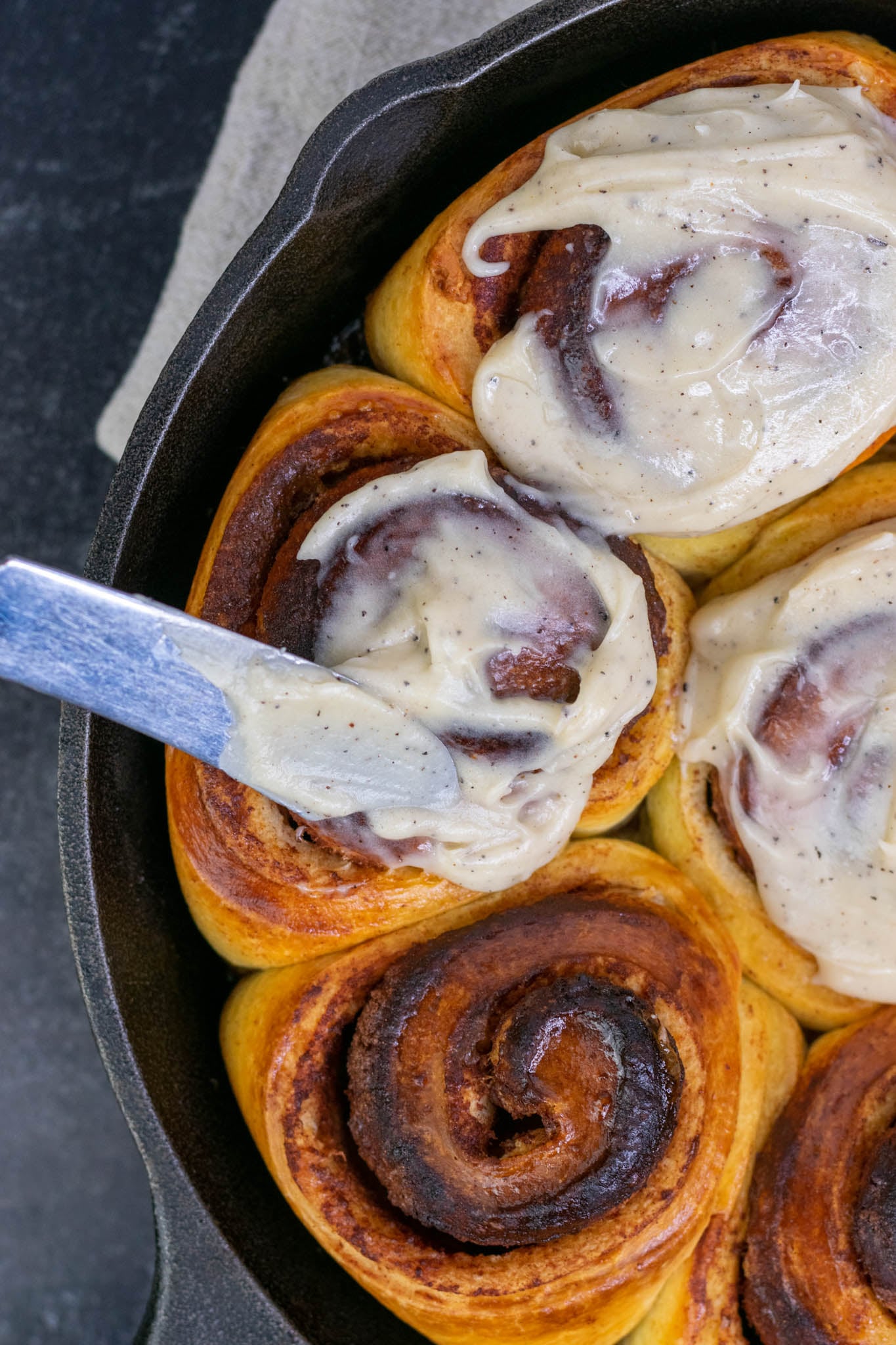 Smearing frosting on Sourdough cinnamon rolls with a butter knife