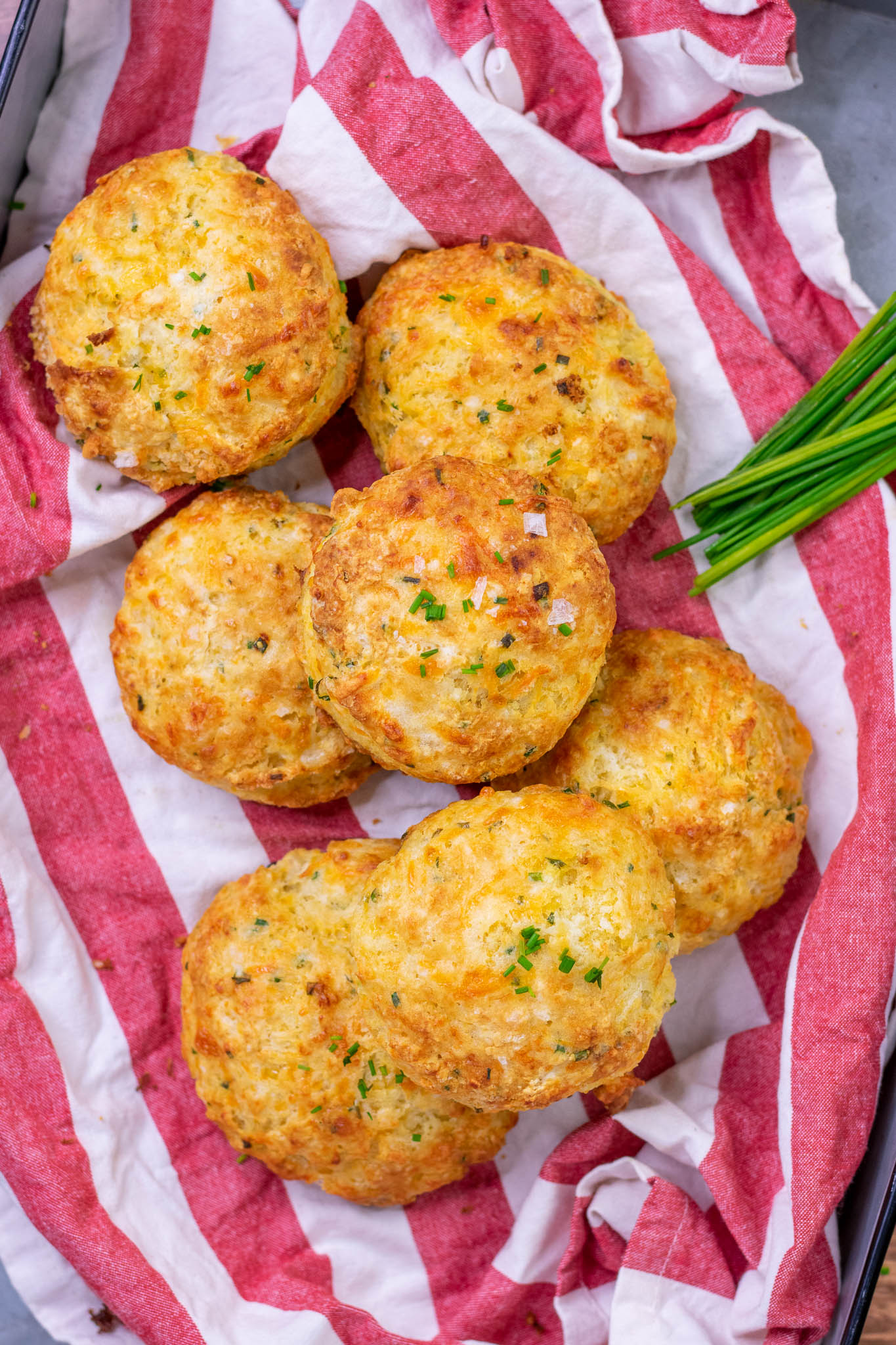 Basket of sourdough biscuits with cheddar and chives in a basket with a red and white striped towel