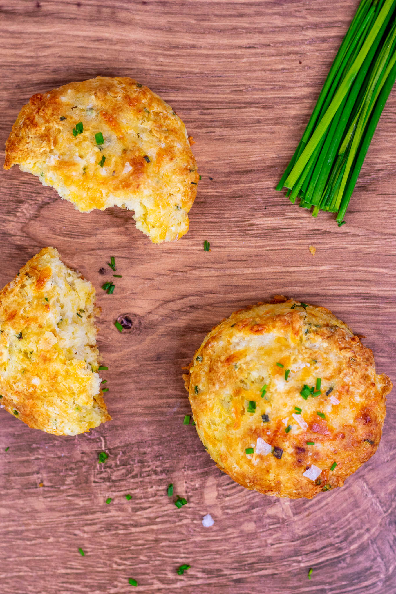 Cheddar Sourdough biscuit broken apart and another one intact on table with chives