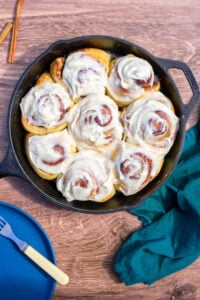 Sourdough cinnamon rolls with brown butter cream cheese frosting in a cast iron skillet