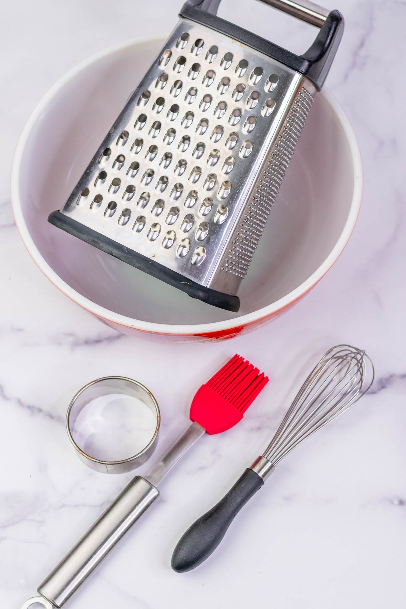 Mixing bowl with box grater, whisk, biscuit cutter, and pastry brush