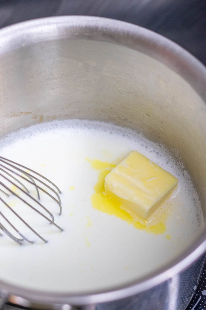Butter melting in saucepan with scalded milk Whisking in butter into scalded milk in saucepan