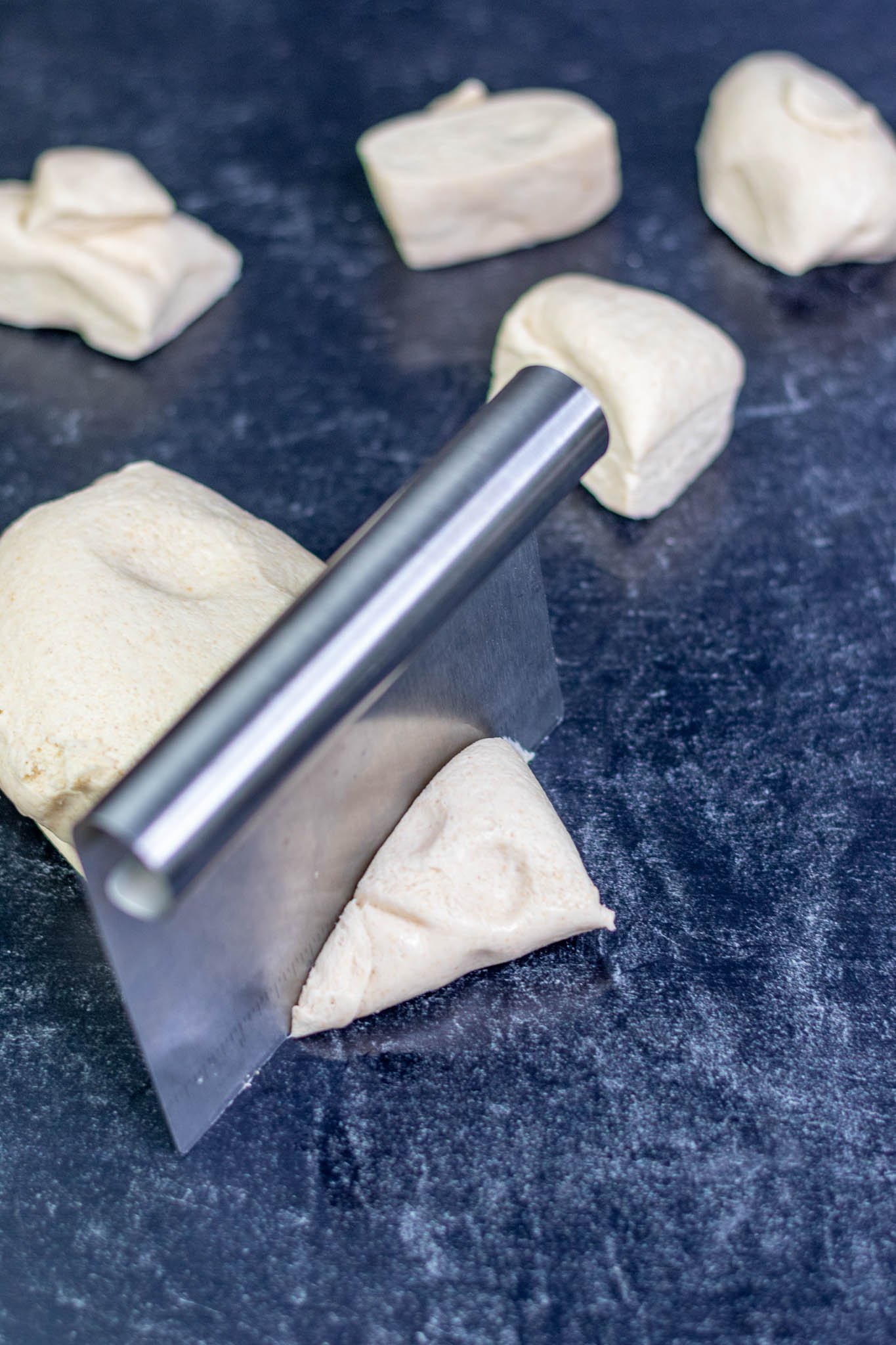 Dividing English muffin dough with bench scraper