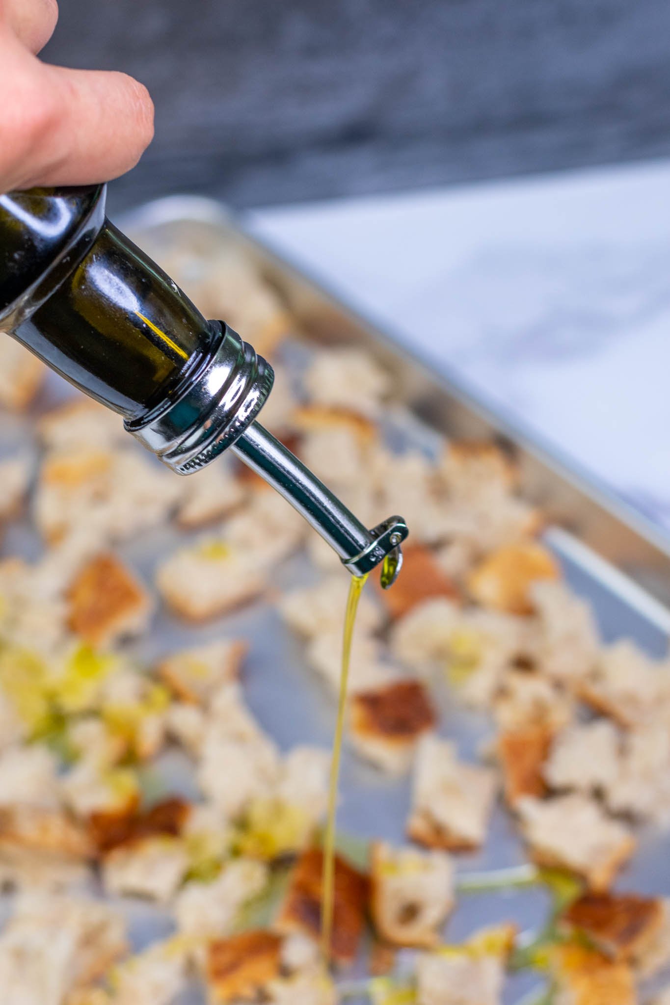 Drizzling olive oil on sourdough croutons