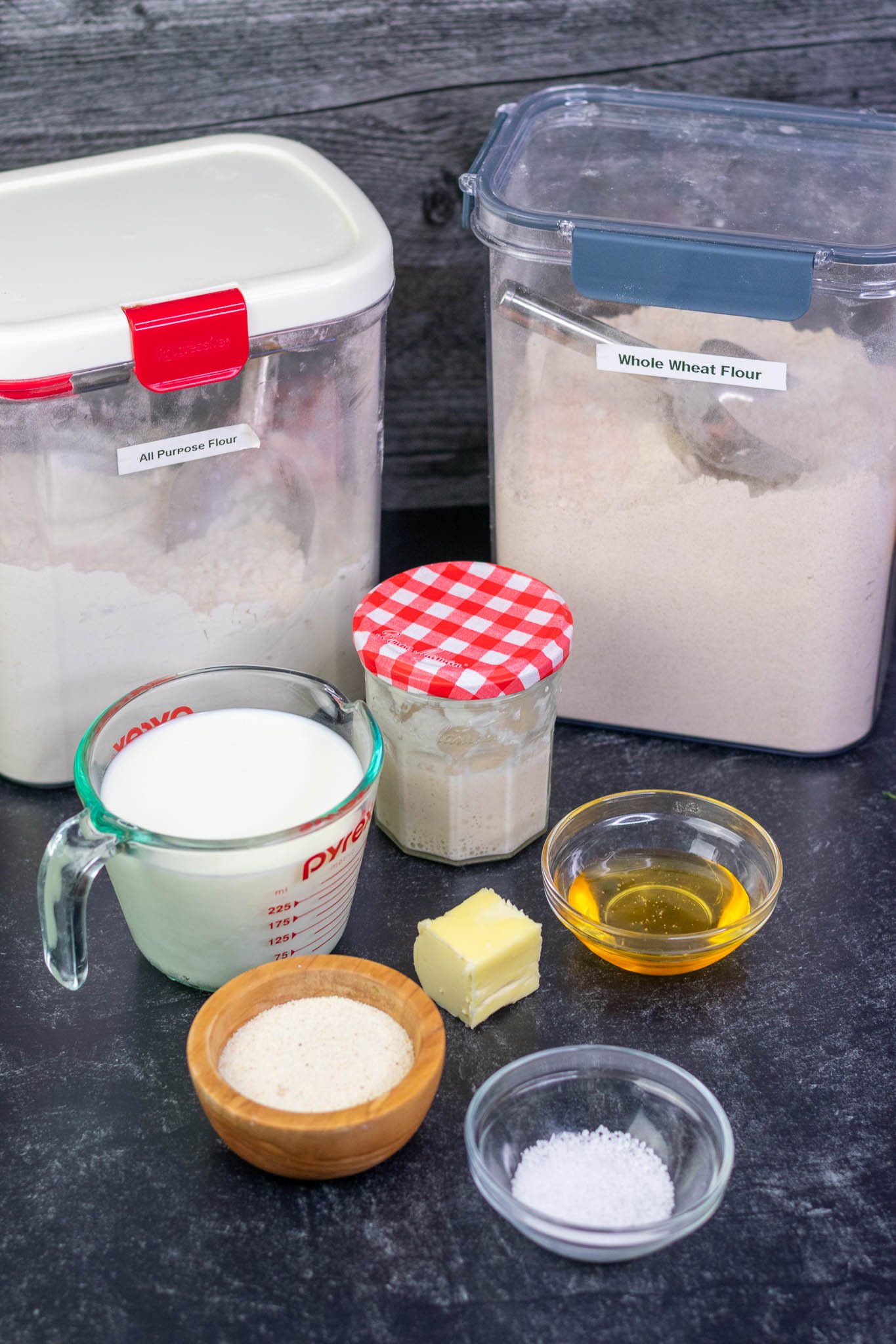 Ingredients needed for sourdough english muffins including flours, starter, milk, honey, butter, salt, and semolina