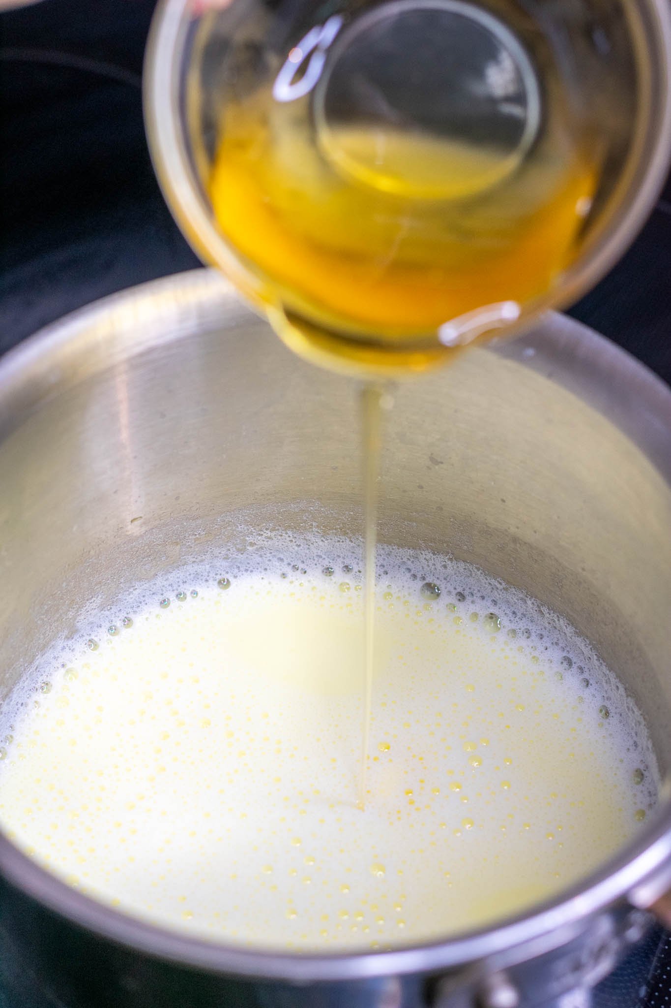 Adding honey to scalded milk in saucepan