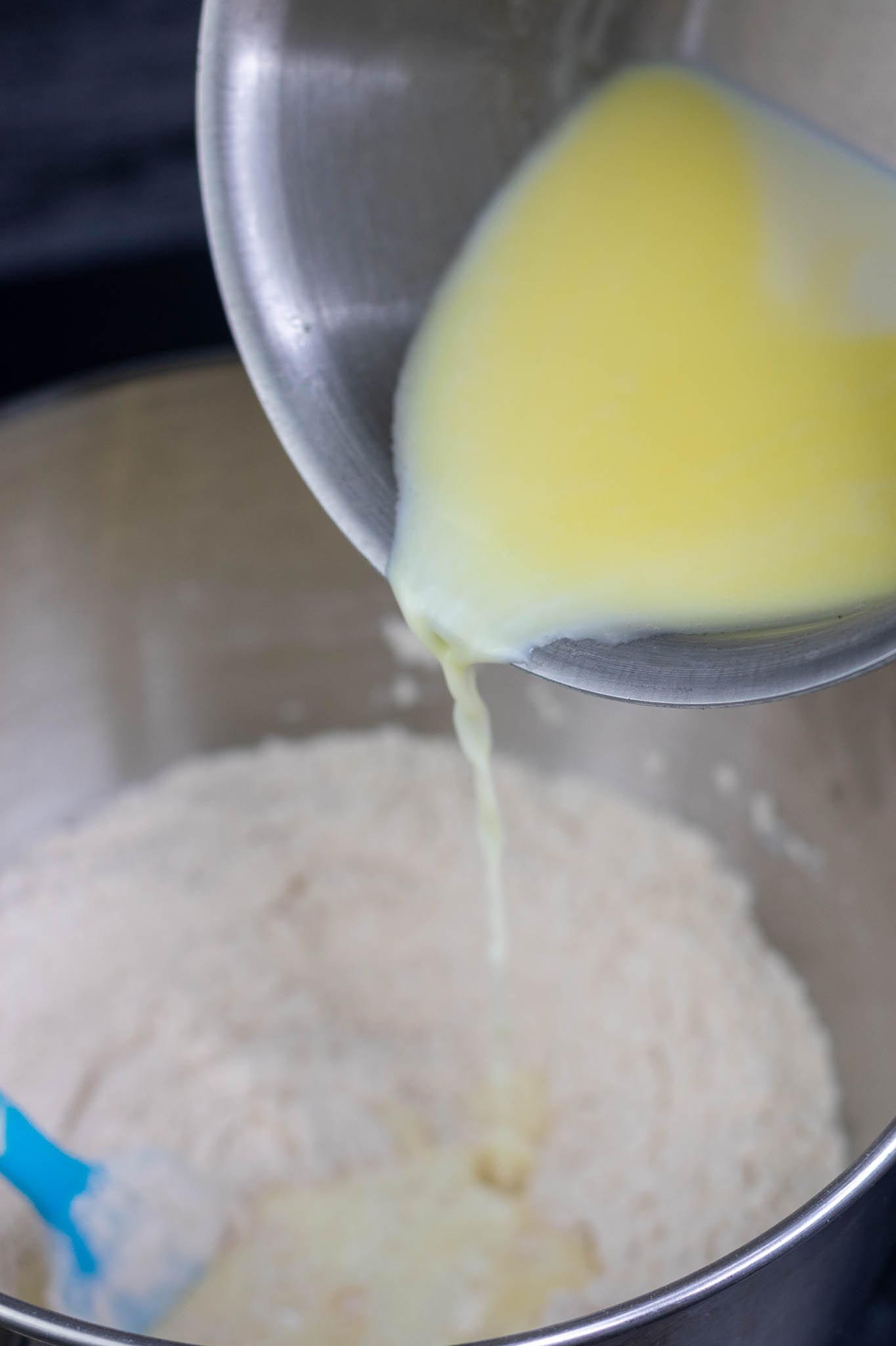 Pouring in scalded milk into english muffin dough