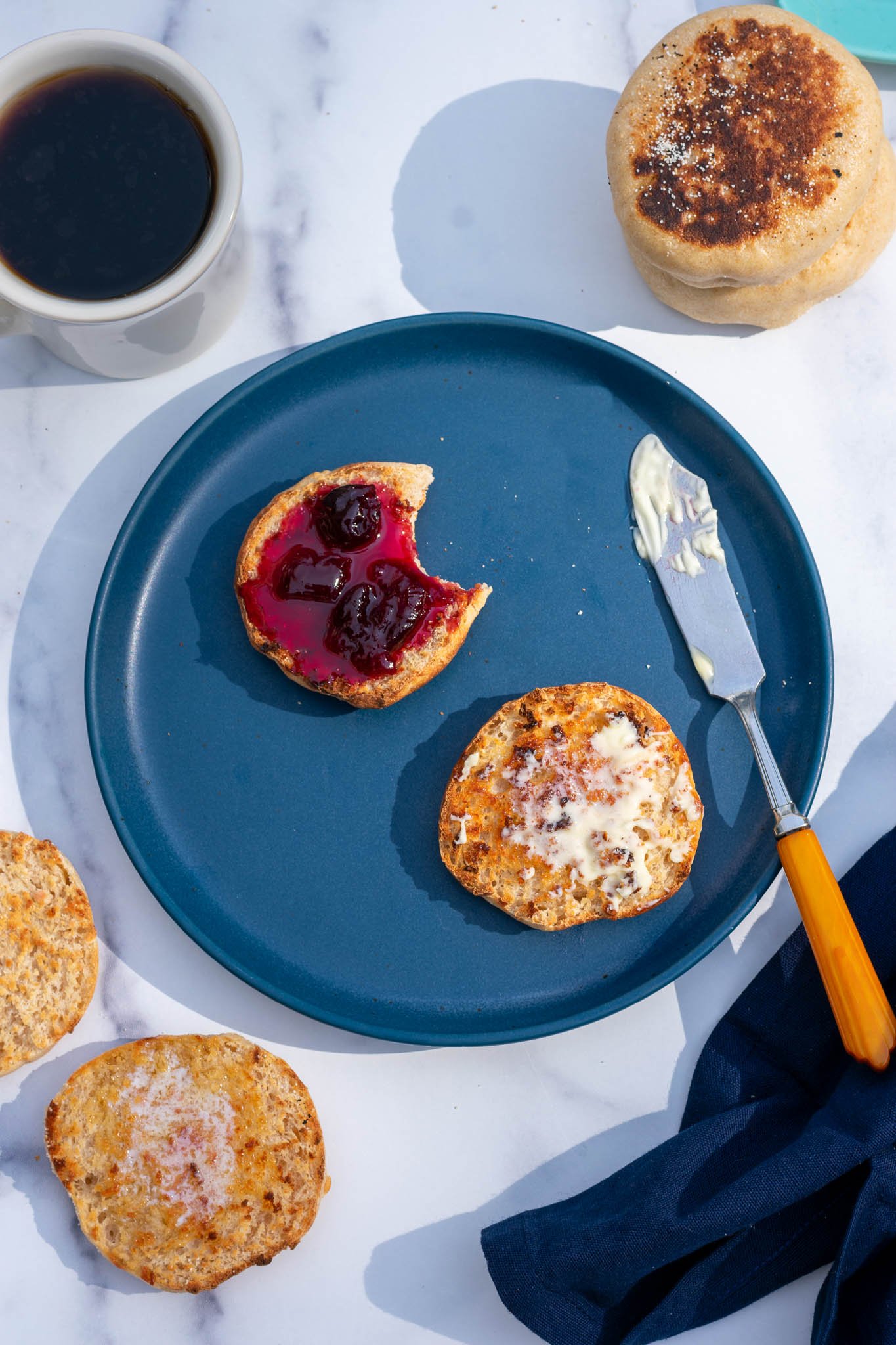 Split sourdough english muffin on plate with butter and jam