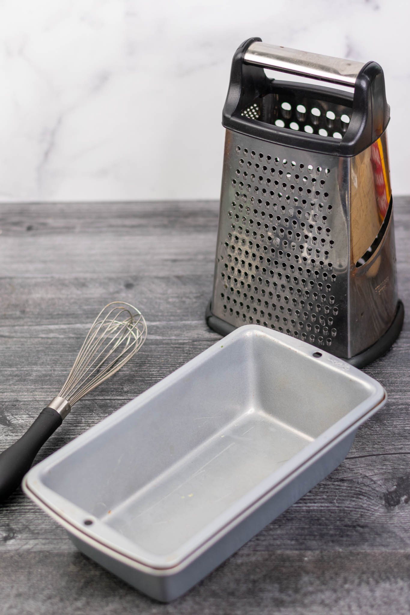 Bread loaf pan, whisk, and box grater