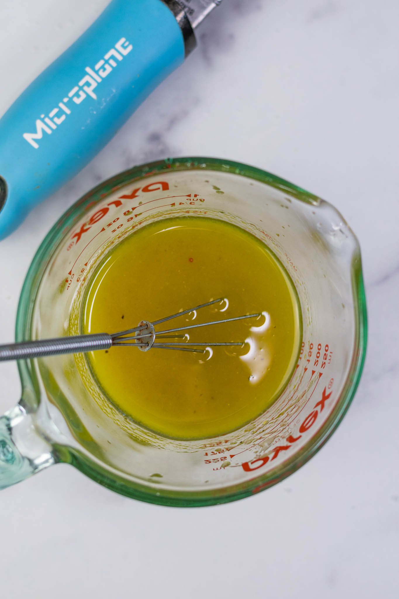 Liquid measuring cup with panzanella vinaigrette and small whisk