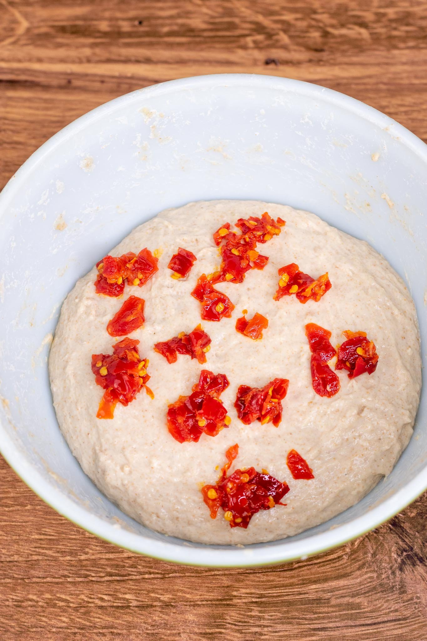 Calabrian chilis added on top of dough in bowl
