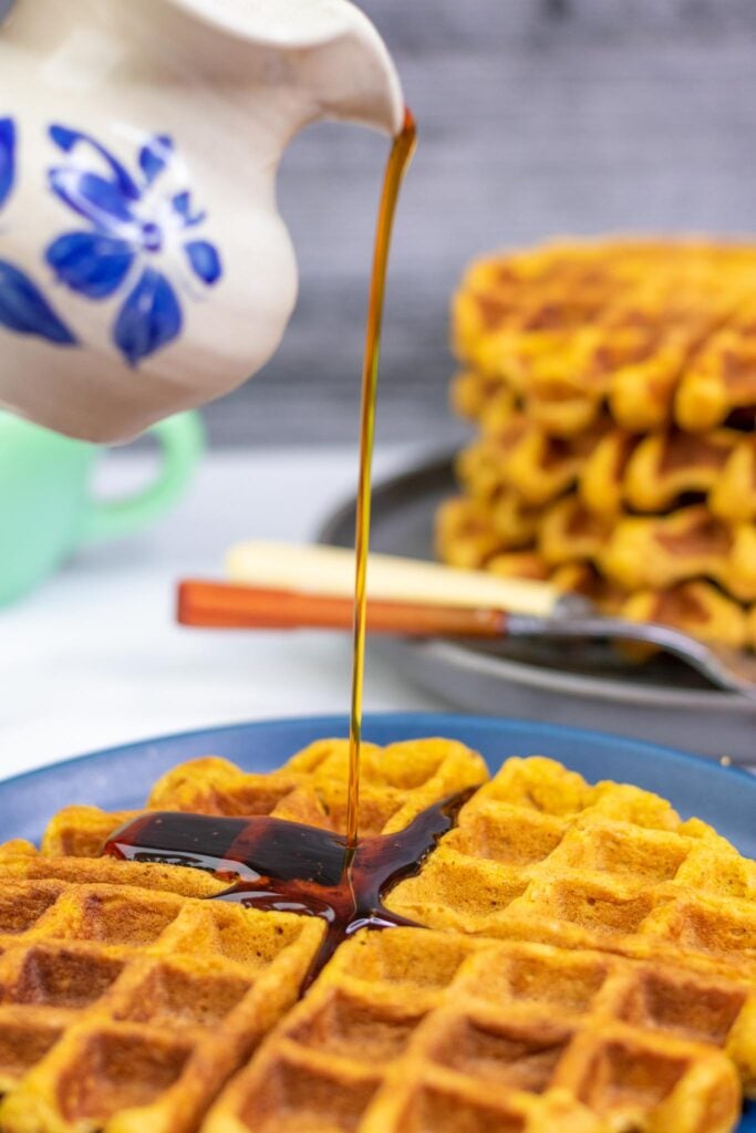 Pouring maple syrup onto Sourdough Pumpkin Waffles