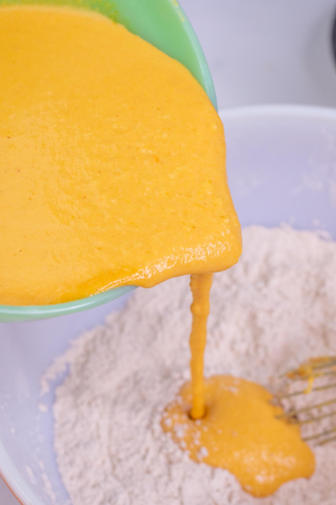 Pouring wet ingredients into dry ingredients bowl